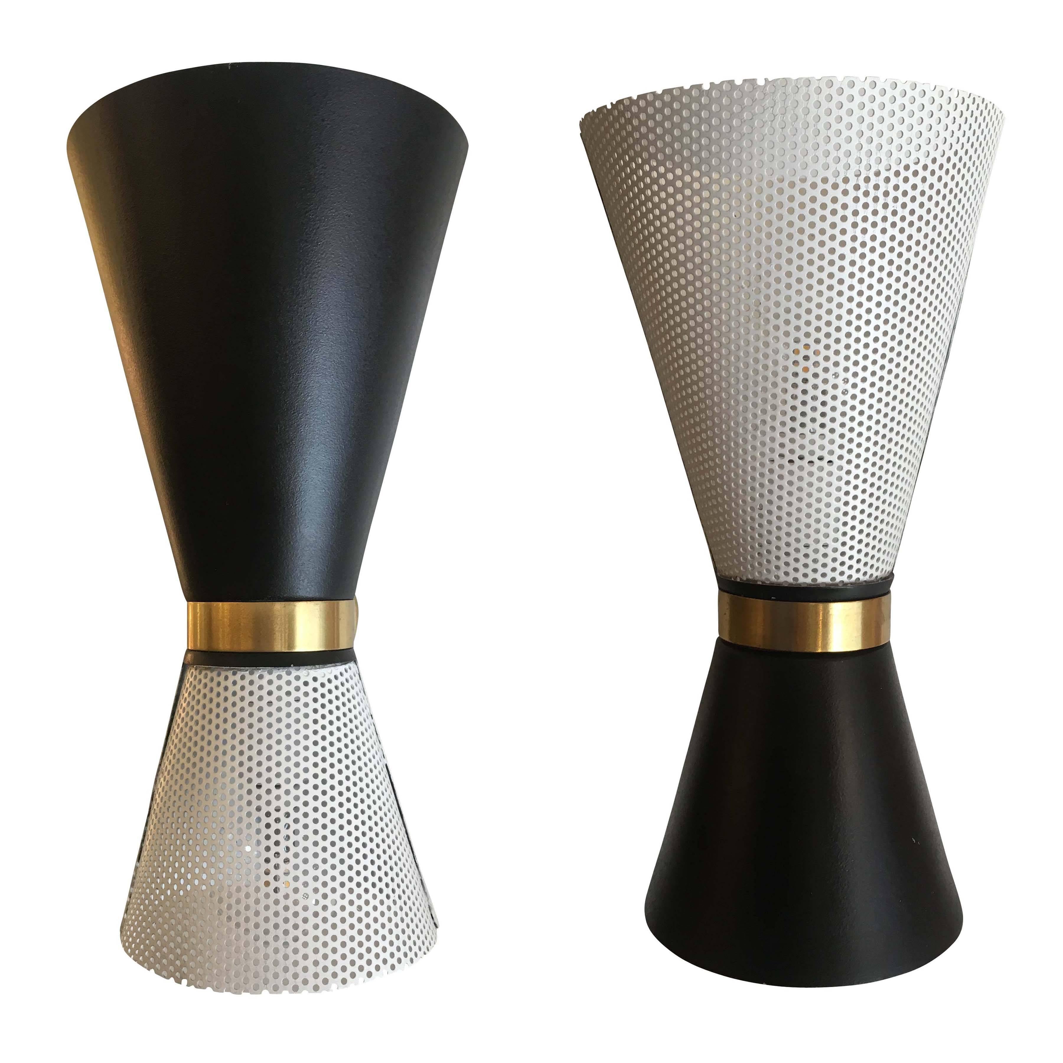 Alternating black and white perforated sconces by Stilnovo from the 1960s. Back plate and centre loop are brass. Each holds two candelabra sockets.