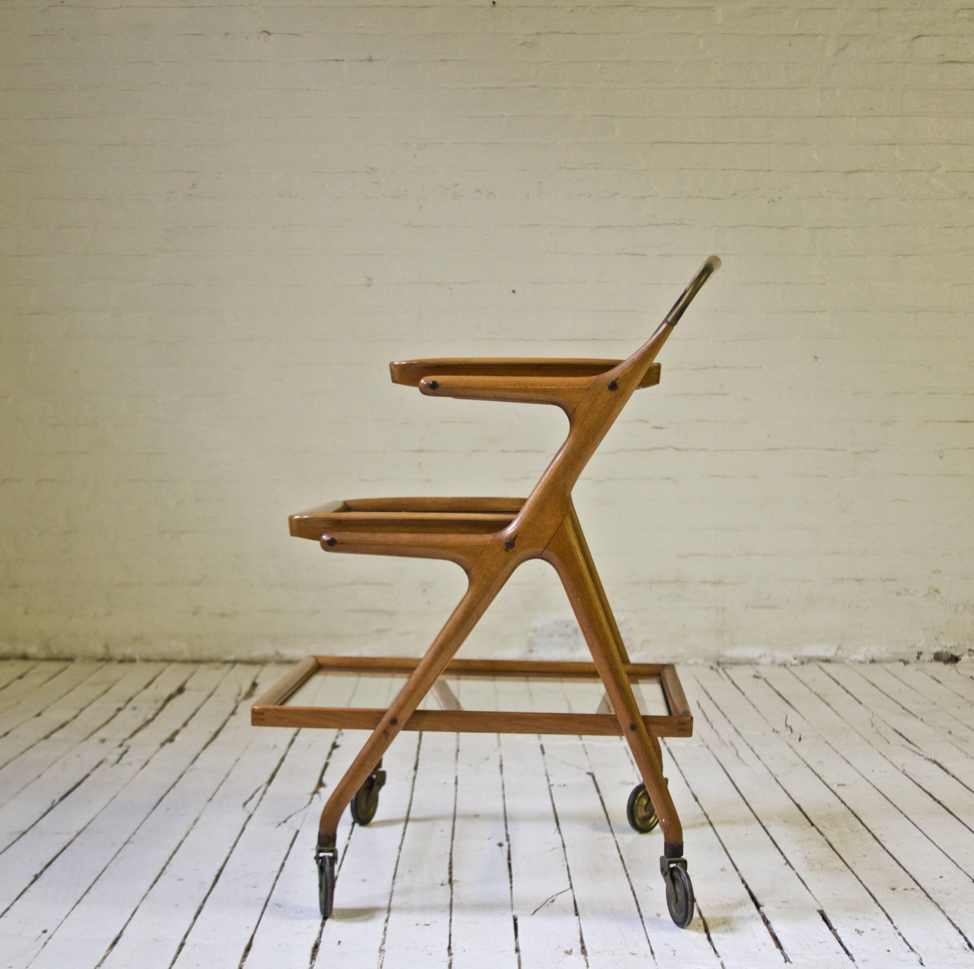 Graceful bar cart or tea trolley in carved Italian walnut and brass. Manufactured in Italy by Cassina, circa 1955. The two upper trays are removable for service. Excellent construction; nice patina showing age and use.