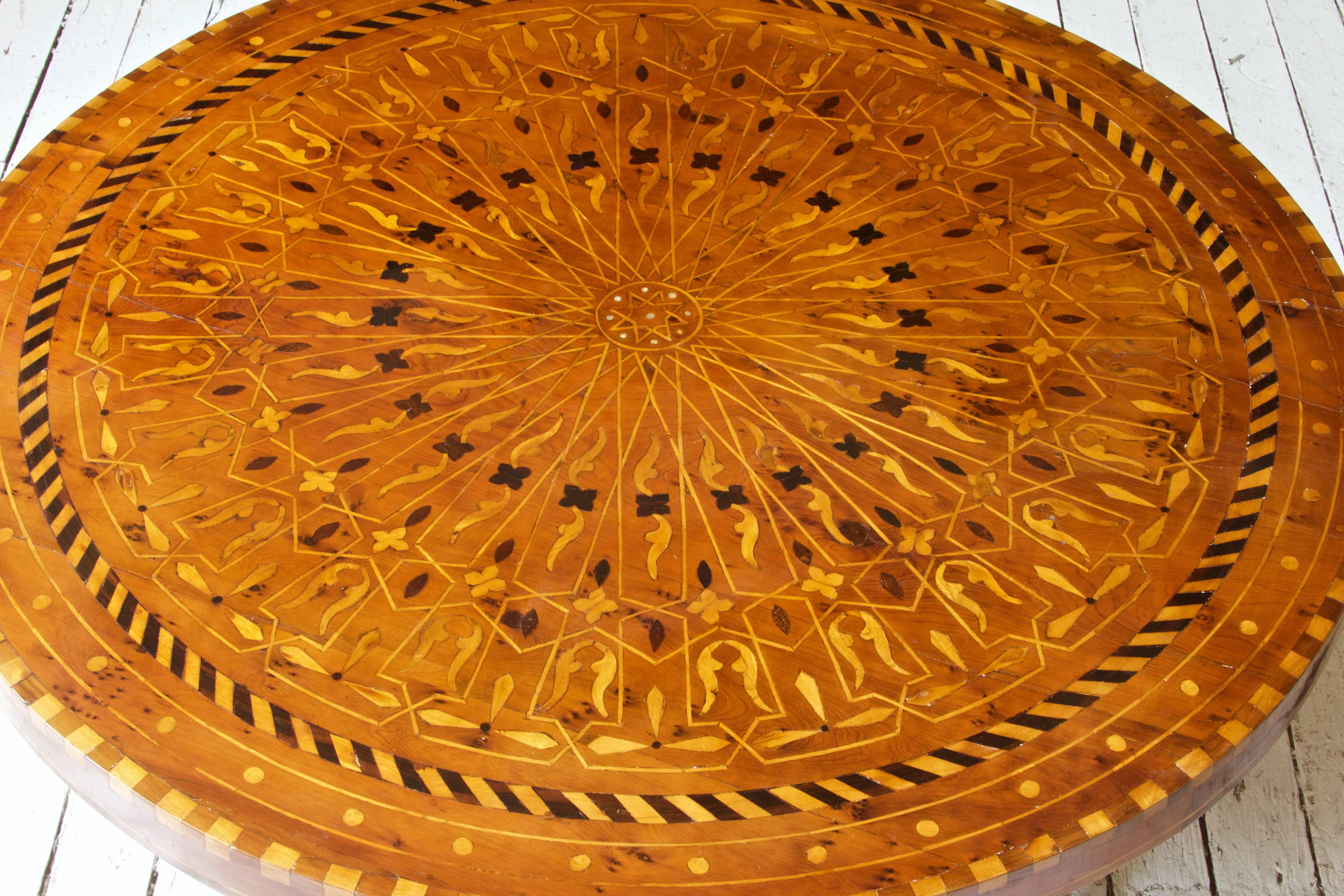 Antique Italian low table with polished intarsia top consisting of fruitwood, walnut, ebony and mother of pearl-typical of the Neapolitan school of the late 19th-early 20th centuries. Iron base consists of four columnar legs connected by circular