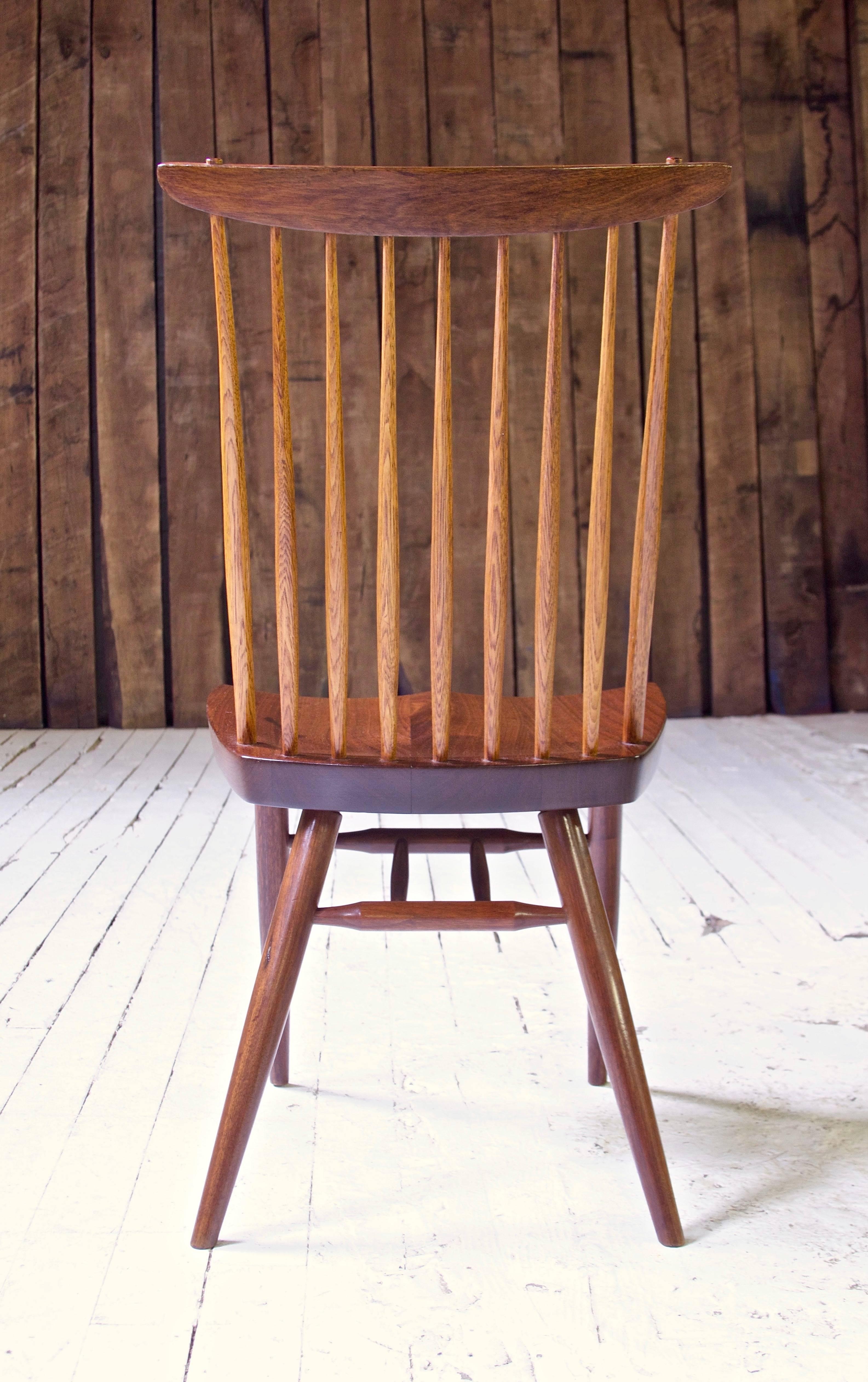 A well-preserved early 'New Chair' in black walnut and hickory, handmade by George Nakashima in his New Hope studio in the mid-late 1950s. Handplane and chisel marks are visible on the hand-hewn Hickory spindles, the turned leg stretchers' tenons
