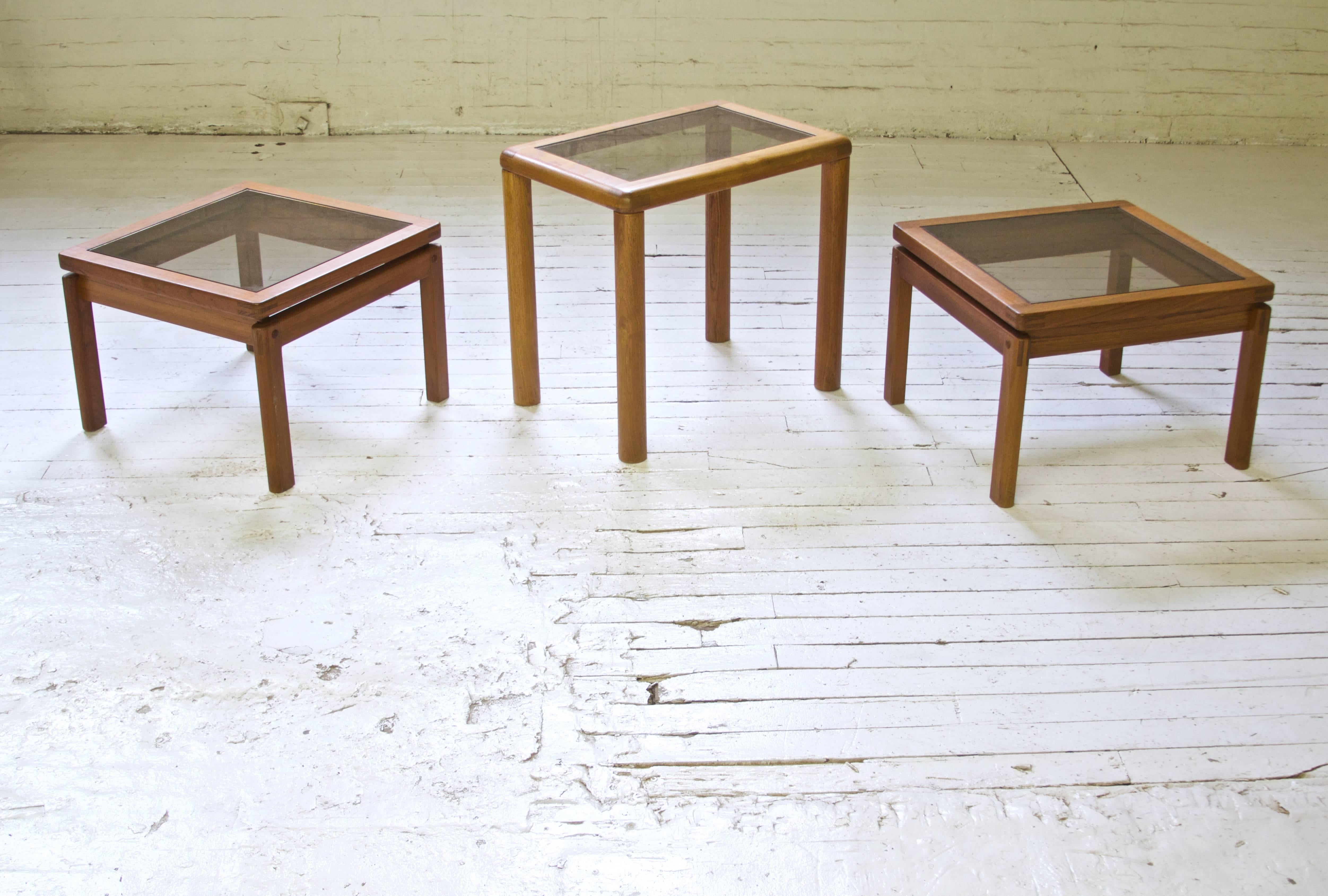 Set of three oiled teak occasional tables with exposed bridle joinery and smoked glass tops. Excellent construction, stamped made in Denmark.

Larger table's dimensions:

H: 22
