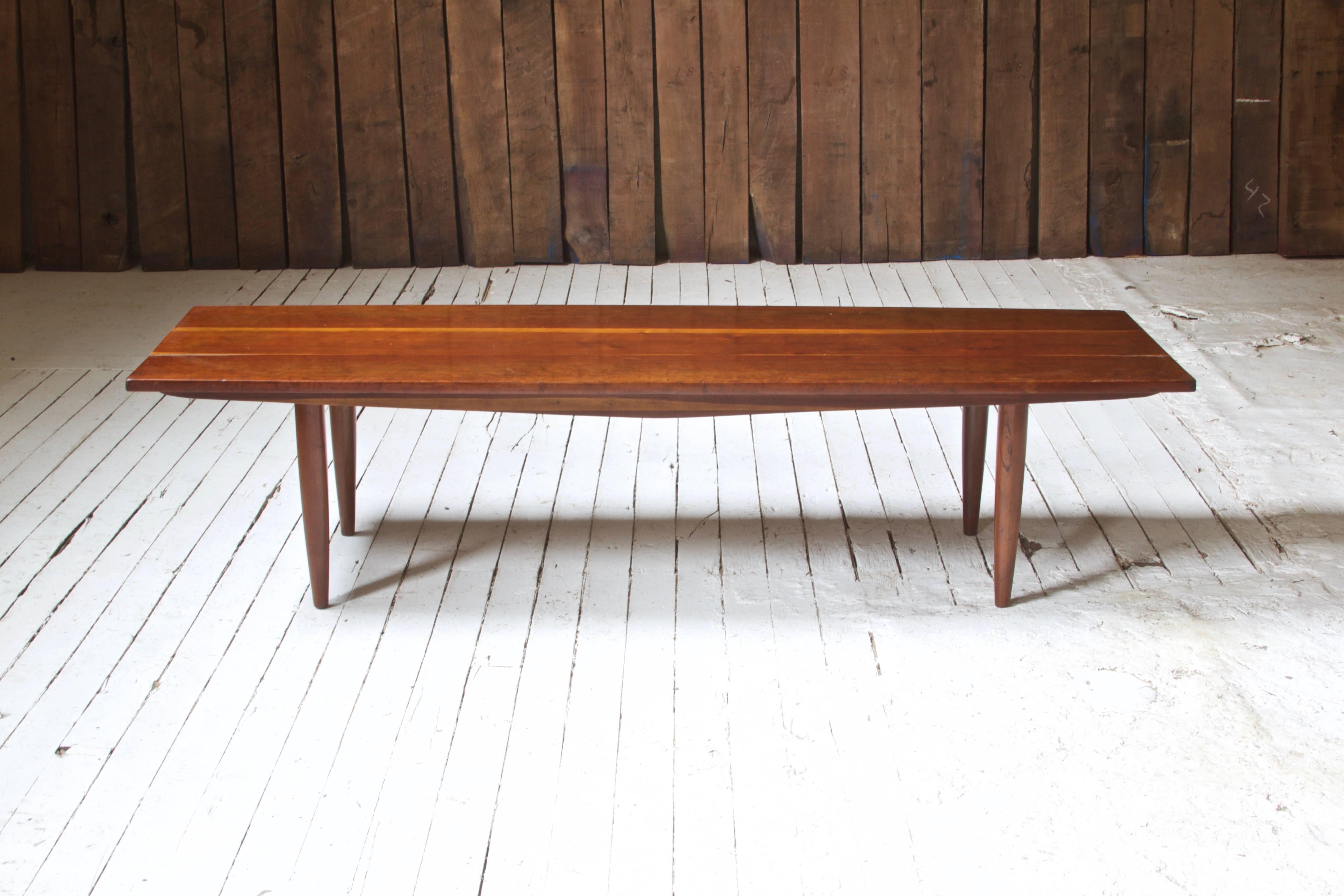 Long coffee table by Phillip Lloyd Powell with turned legs and solid figured cherry top. Rich patina in the cherry boards; an excellent example of studio craftsmanship.