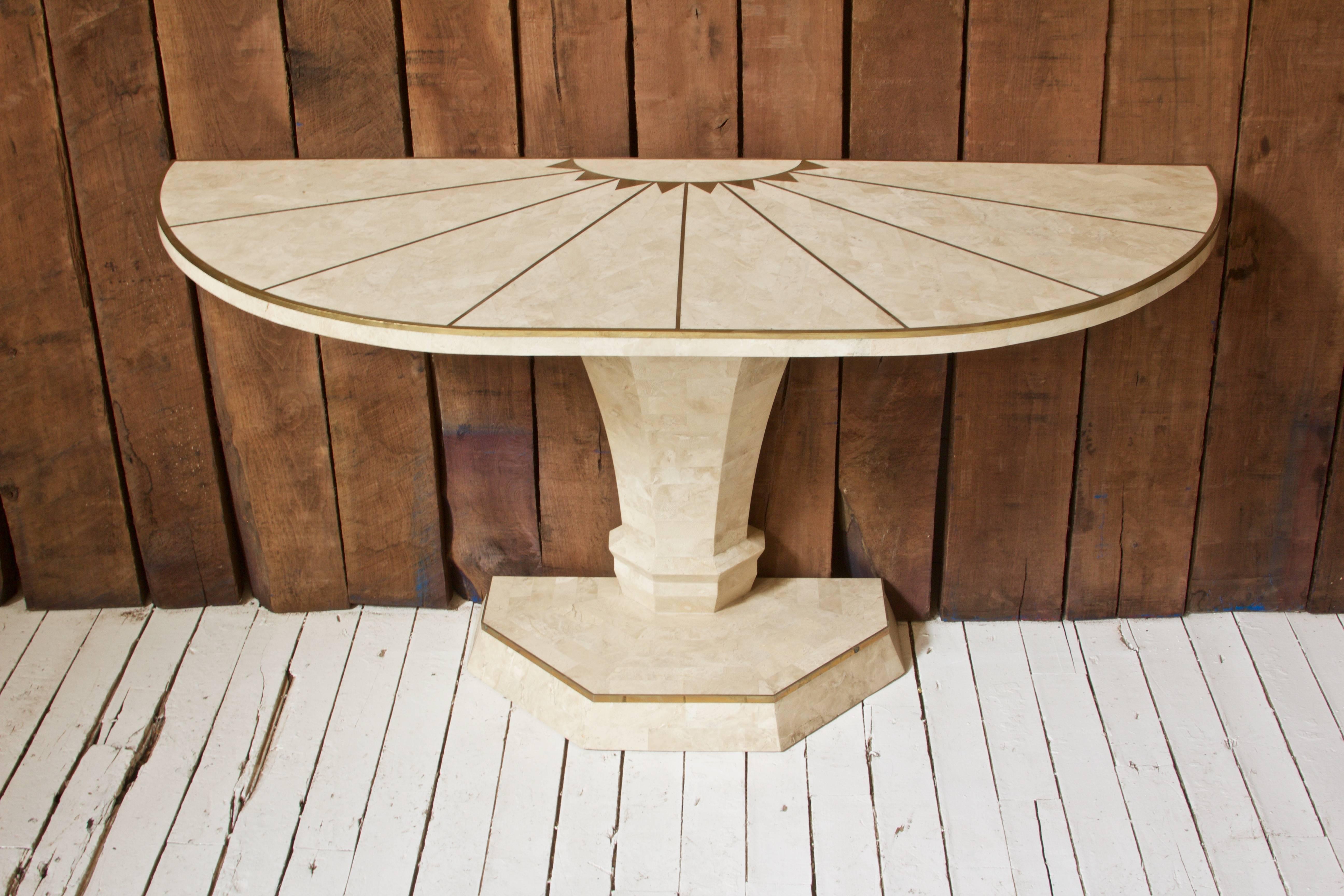 Lovely vintage tessellated travertine and brass inlay demilune console table designed by Maitland-Smith; made in Italy for export, circa 1970. Excellent hand craftsmanship visible throughout, inlaid sunburst brass pattern to top. Geometric pedestal