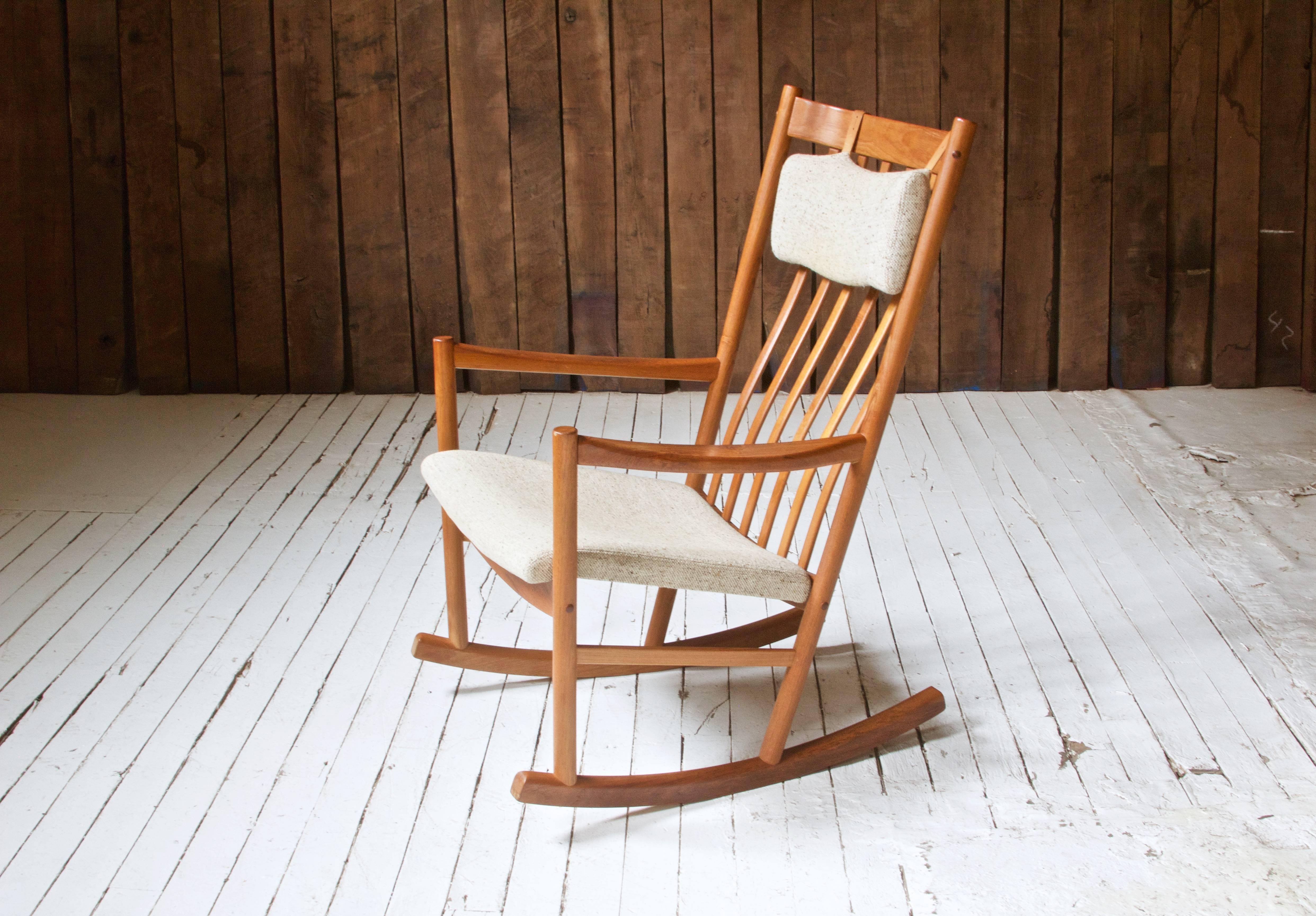 A handsome, generously proportioned rocking chair with turned, steam-bent, and joined teak frame; designed by Hans Wegner for Tarm Stole, 1960s. This example retains the original wool upholstery to seat and head cushion as well as its manufacturer's