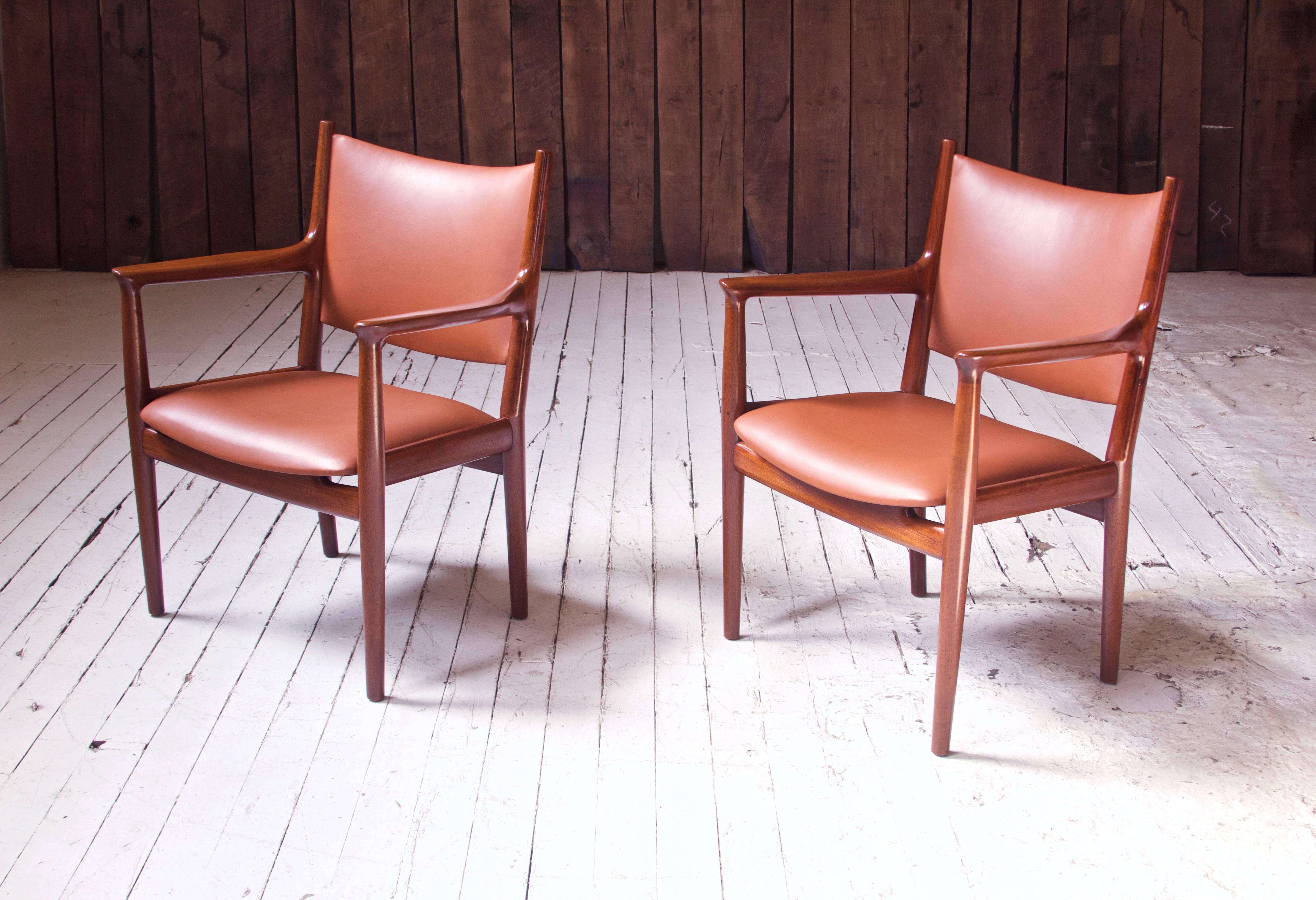 Handsome pair of vintage Hans Wegner for Johannes Hansen JH-513 teak and cognac leather conference chairs. Wegner's conference chairs of this period take inspiration directly from Designmuseum Danmark's own 18th century 'Spanish Travelling Chair',