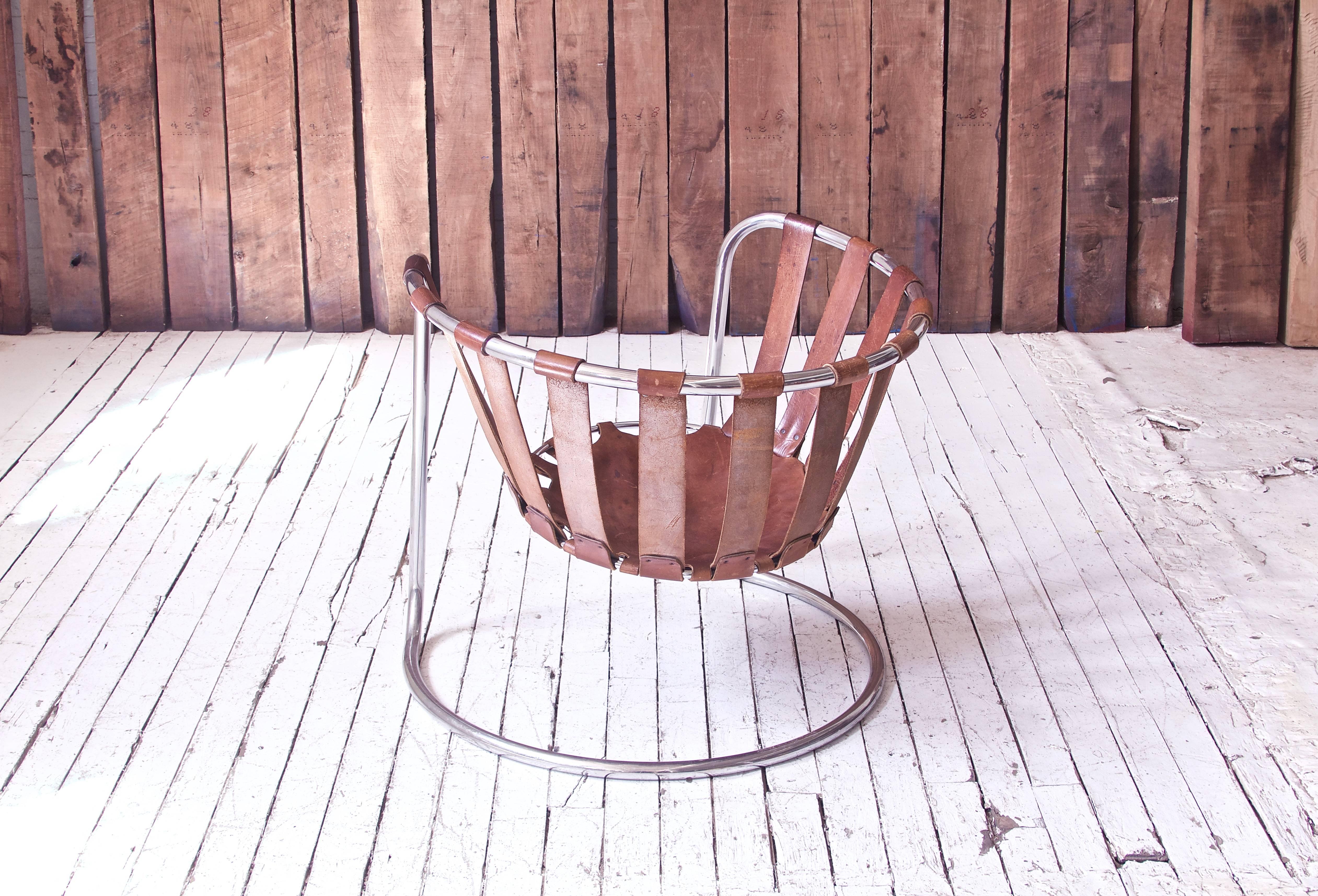 An interesting vintage French leather strapped sling chair, unique in design and surprisingly comfortable. The open, bent metal frame flexes and bounces to support the sitter in a weightless, completely suspended seat. Quality construction/leather