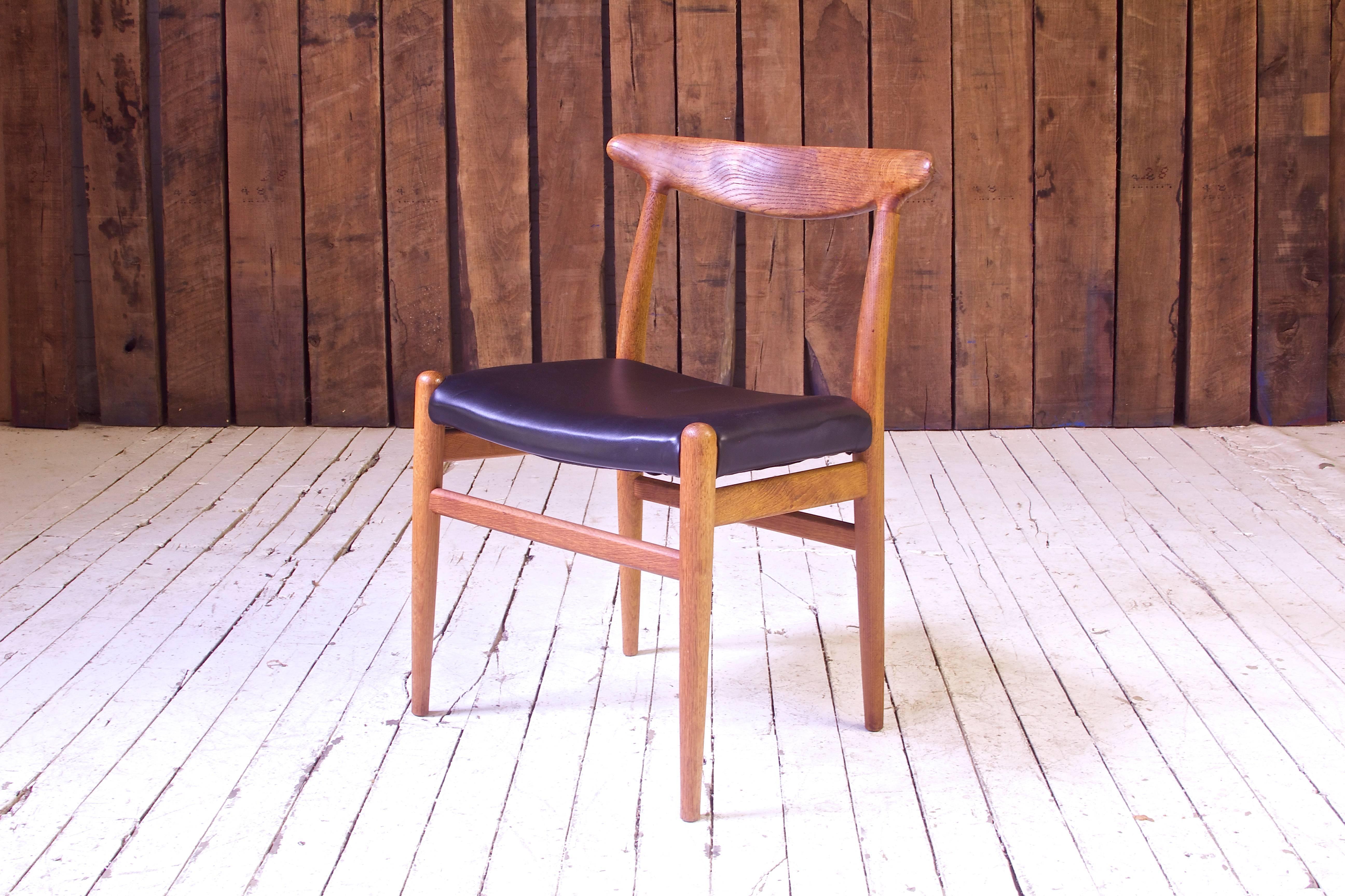 A lovely example of the early work of the 20th century's master of seating design, Hans J. Wegner. The sculpted oak backrest or top-rail employed here was developed as part of a family of innovative seating designs of the 1950s including Wegner's
