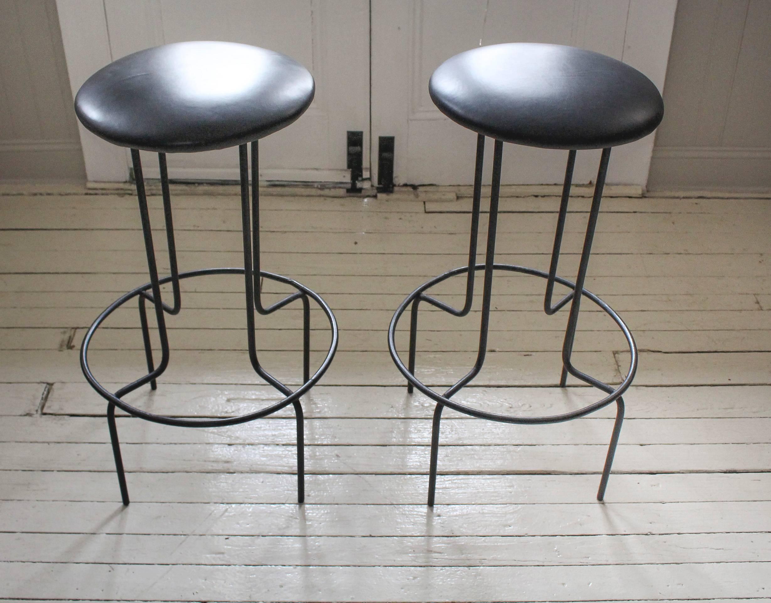 Pair of iron bar-height stools, 1950s USA, with footrest. Newly upholstered black leather seats. Manufacturer's original label is still intact and attached; it reads 