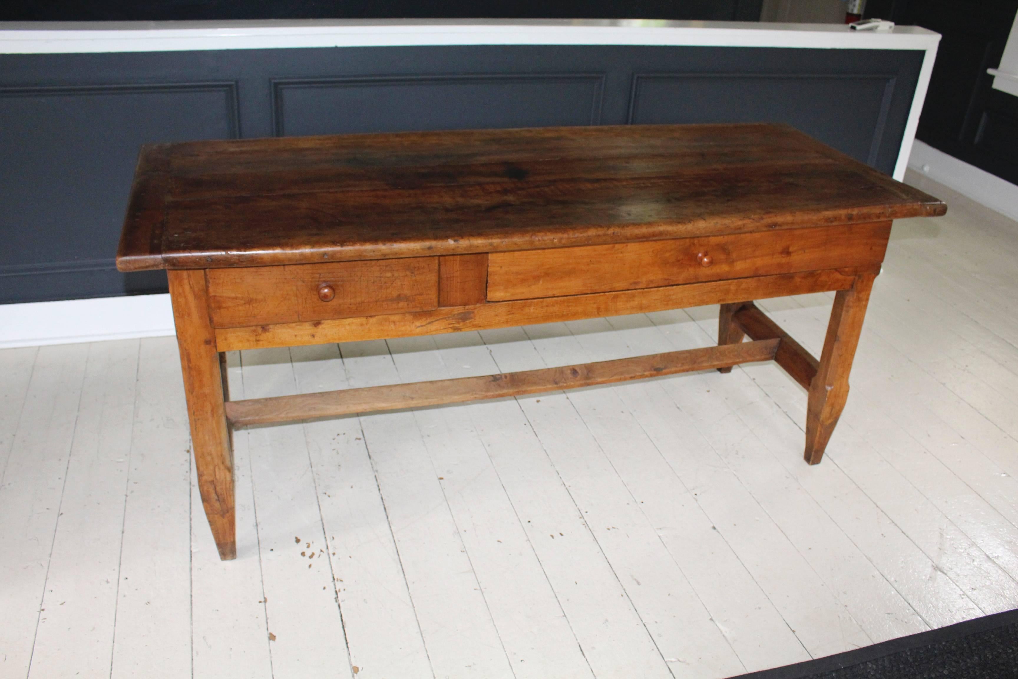 19th century France 'Grassoise' farm table with secret hiding compartment concealed behind right-hand elongated sliding drawer door. Tabletop has breadboard ends and sits atop an angled stretcher base joining tapered legs.