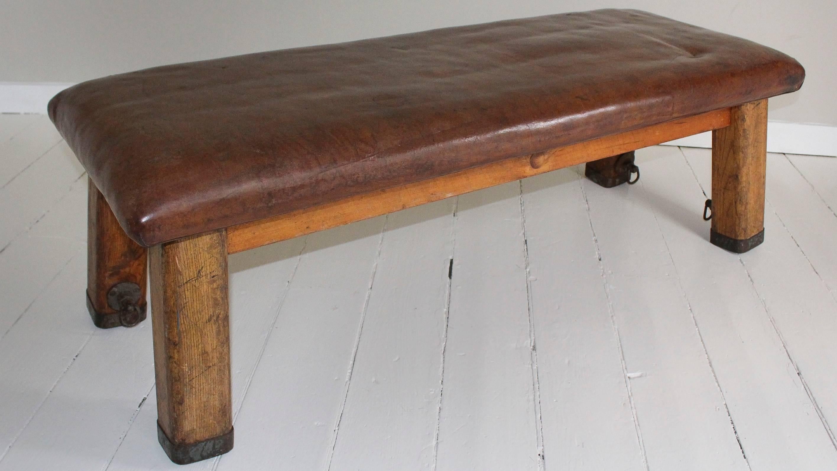 Leather gym bench, 1940s France, with iron surround at base of legs and iron rings bolted to the inside of the legs for securing to the floor.