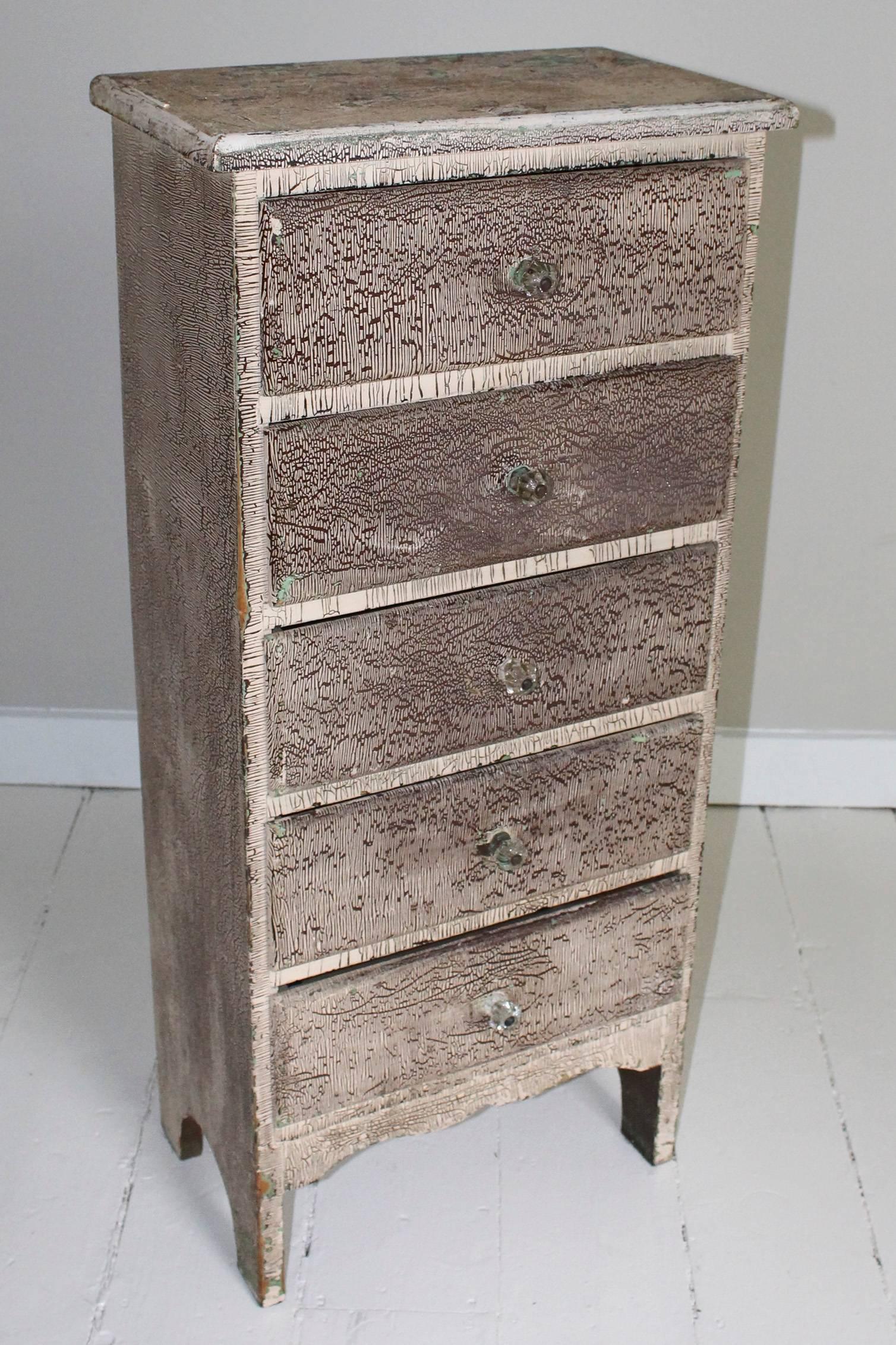 Vintage attic chest of drawers, 1960s USA, with narrow profile, in later crackled paint to front and sides, distressed paint top, green painted plank back. Drawers have glass knobs.