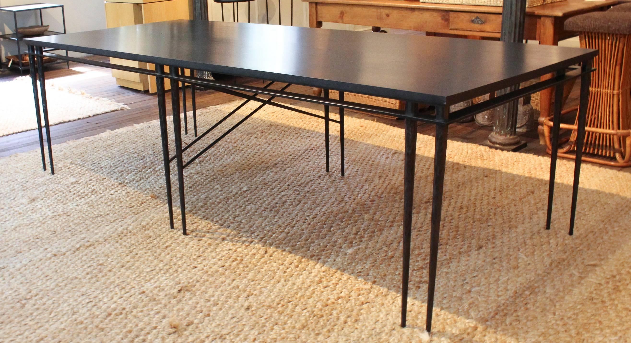 Custom-made dining table of ebonized ash supported by 12 hammered steel tapered legs handcrafted in Belgium. Ash surface has been treated with a protective finish. Table seats eight comfortably.