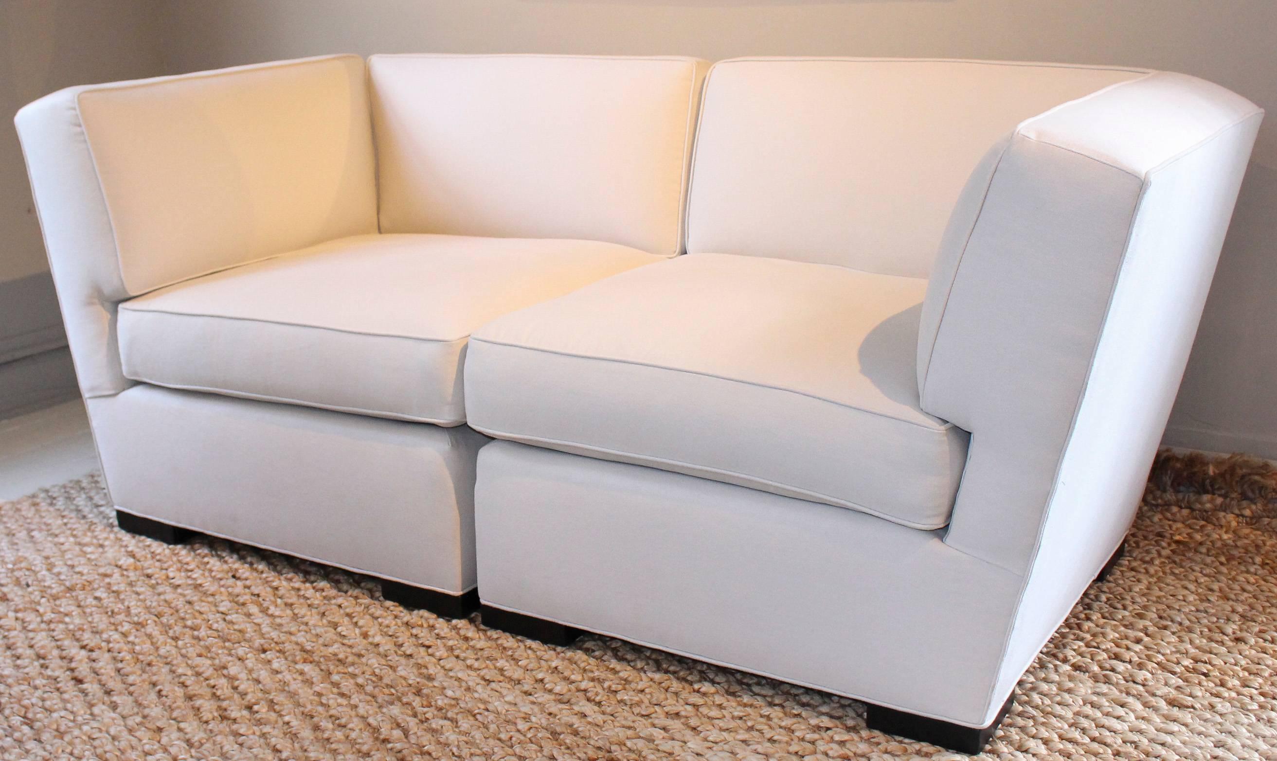 Donghia loveseat with angular armrests newly upholstered in a Rogers & Goffigon cotton. United by interlocking connecting hardware, the sections disconnect to be used as individual chairs.