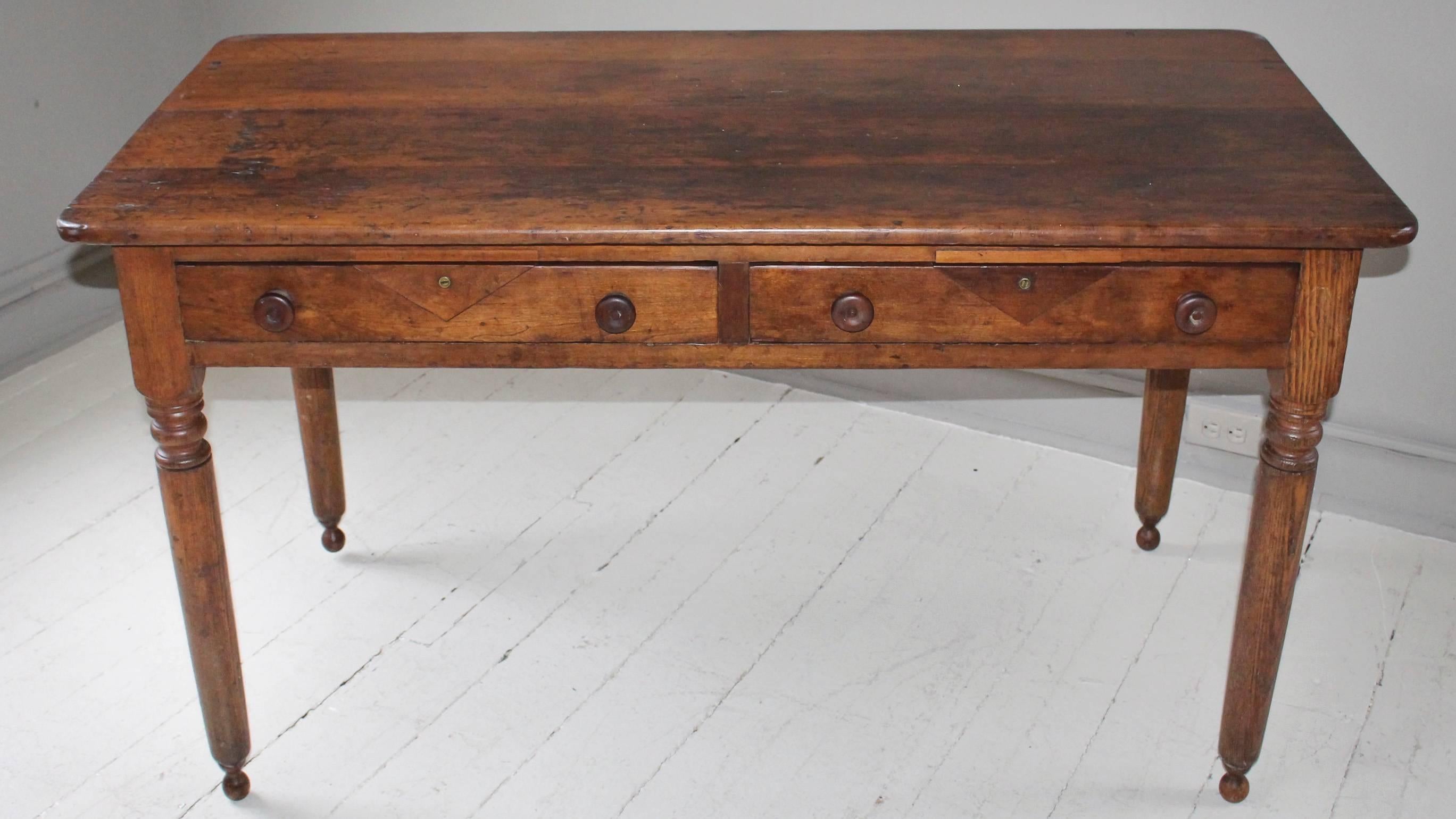 Two-drawer oak table, 19th England, with turned legs ending 'On Pointe'.