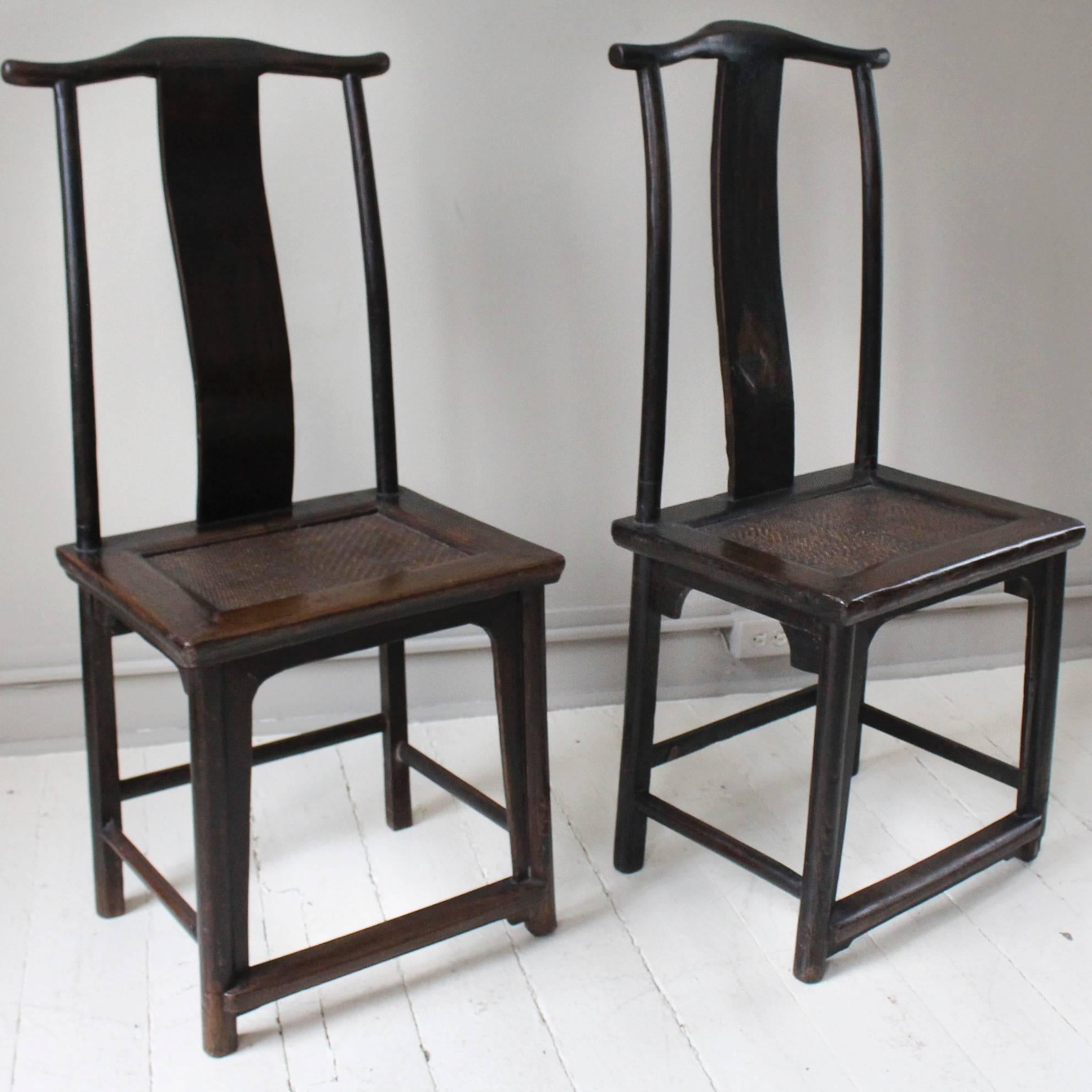 Pair of elmwood, 19th century, Chinese chairs with wide center splats culminating in typical oxen yoke top crest rails and inset woven cane seats. Void of carvings, the chairs have an unadorned simplicity and a wonderful timeworn parina.
  