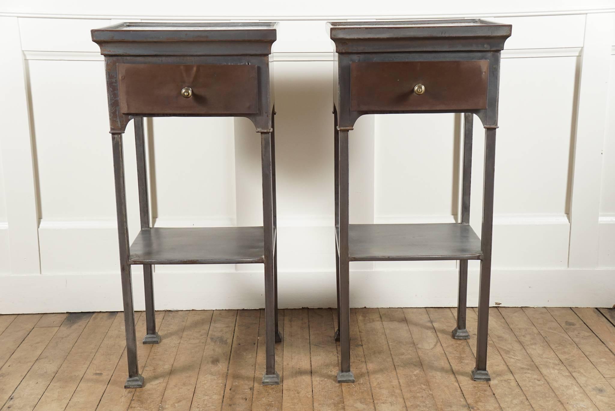 Pair of stripped metal bed stands - old surface patina - tray top with blue and white ceramic insert - over drawer with brass pull - lower shelf supported by square legs - ending in flange style feet - nice details.