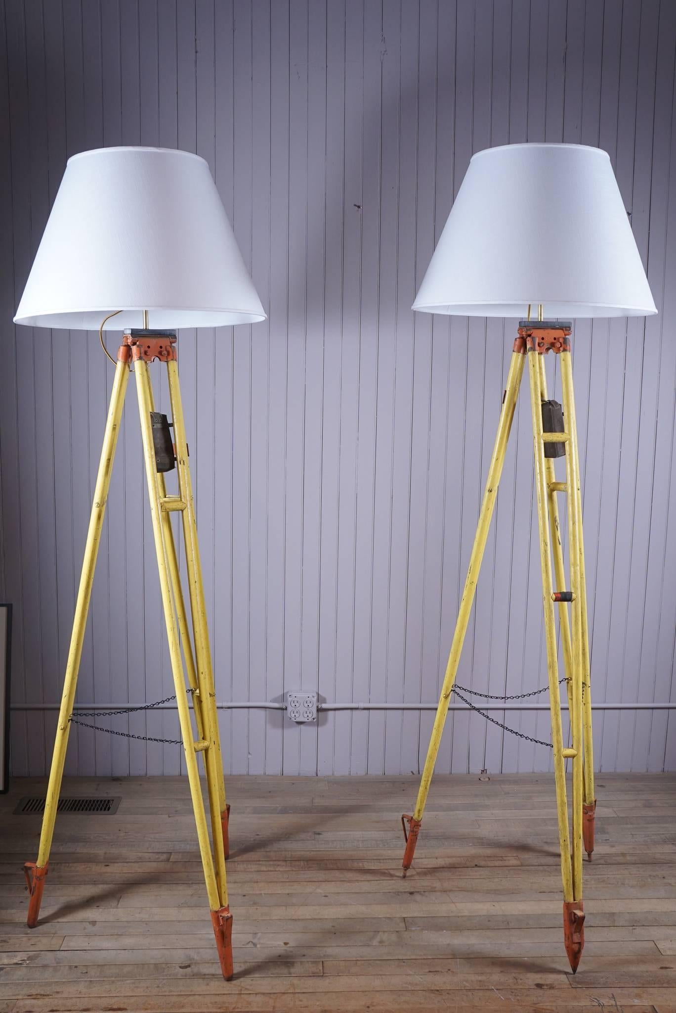 Pair of surveyors stands altered into floor lamps chrome yellow painted wood orange painted metal attachments cloth box.