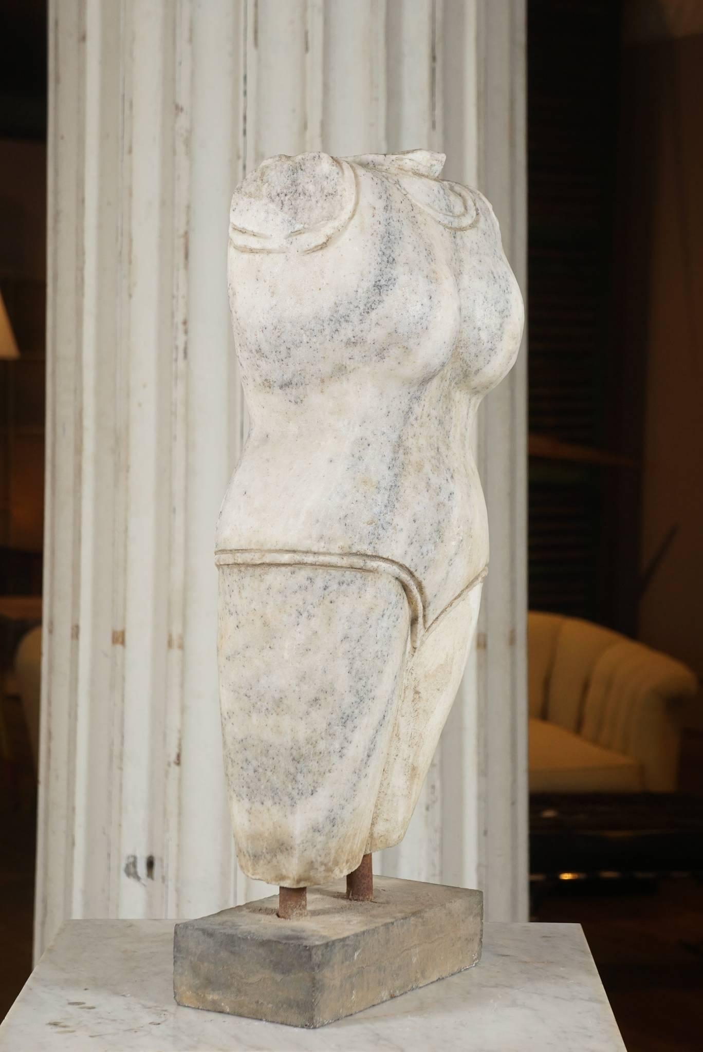 White marble with gray striations, torso of a woman mounted on a stone block, age and origin unknown.