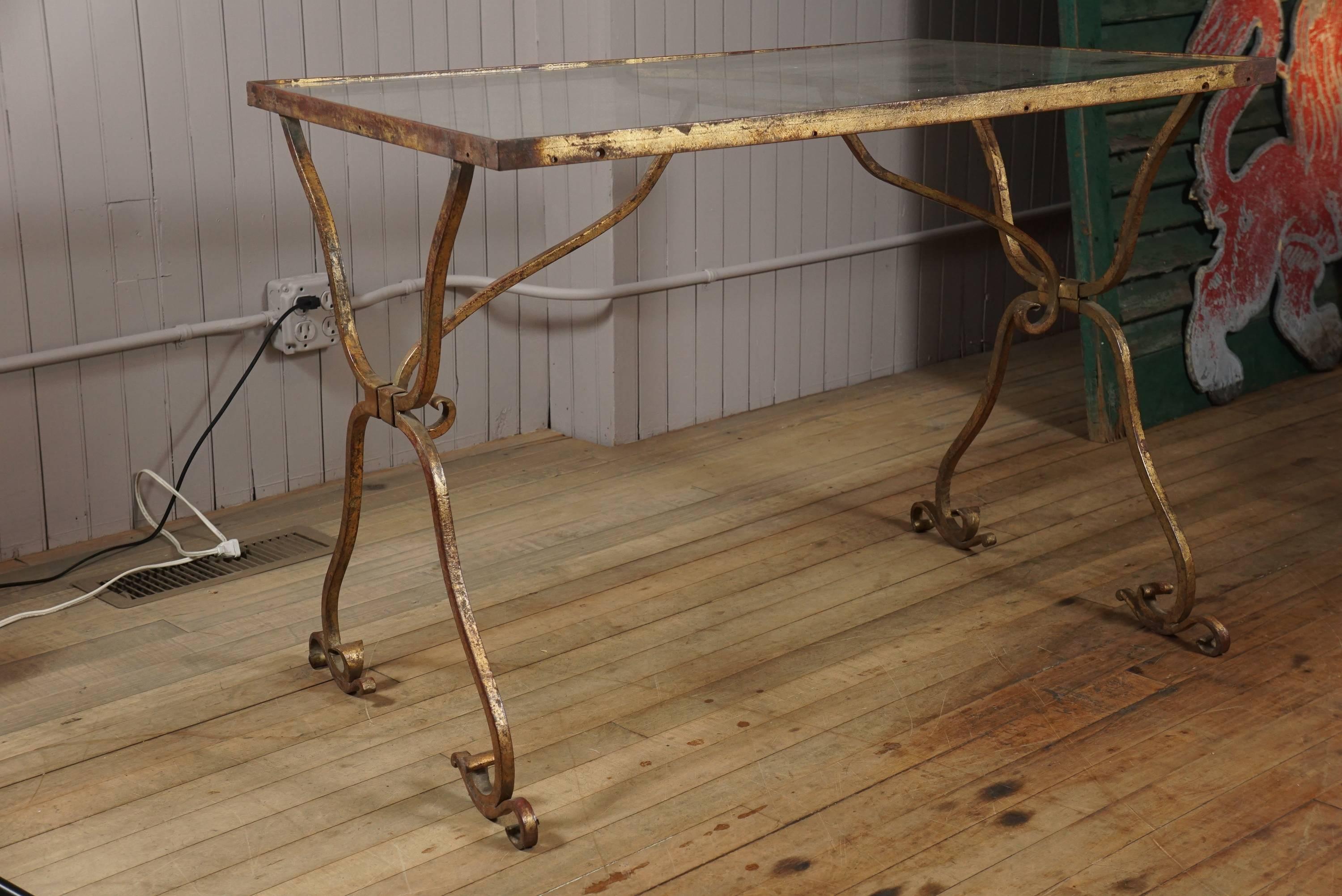 Artistically hand-wrought iron side table with great detail and flourishes, great old gilt patina, new glass top insert.