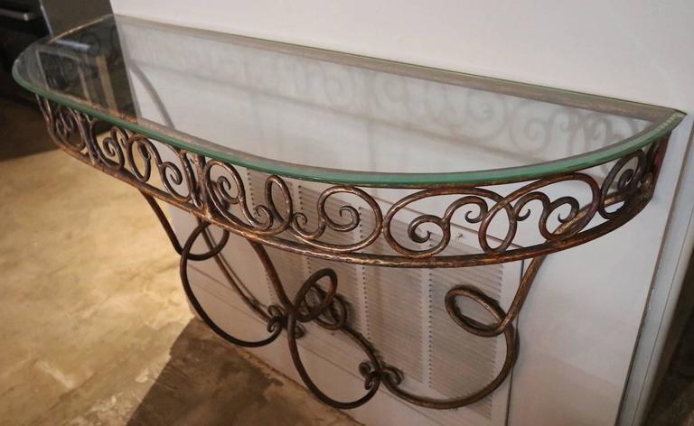 1920s demilune French gilded metal console table with a glass top.