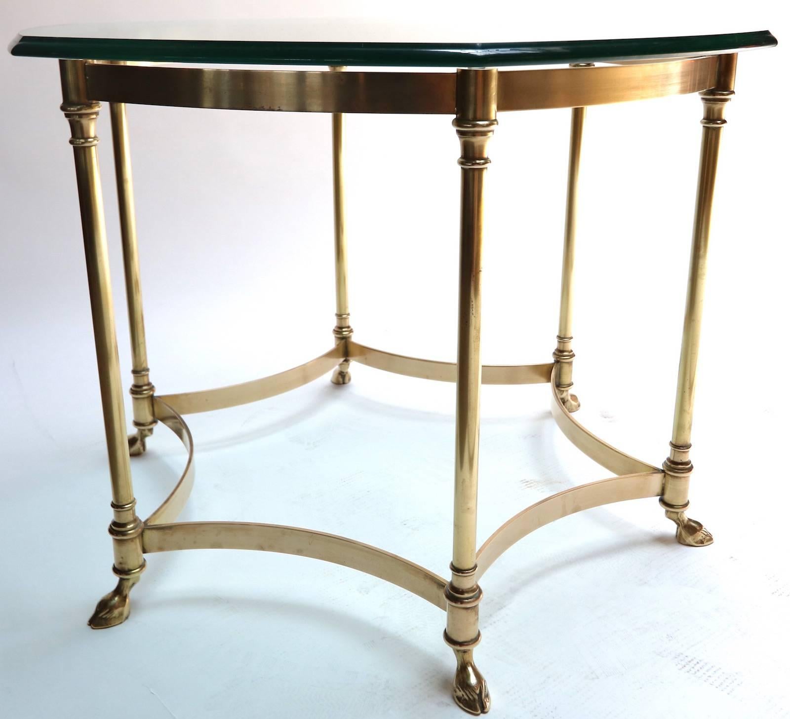 Round brass side table with hexagonal glass top and goat feet.