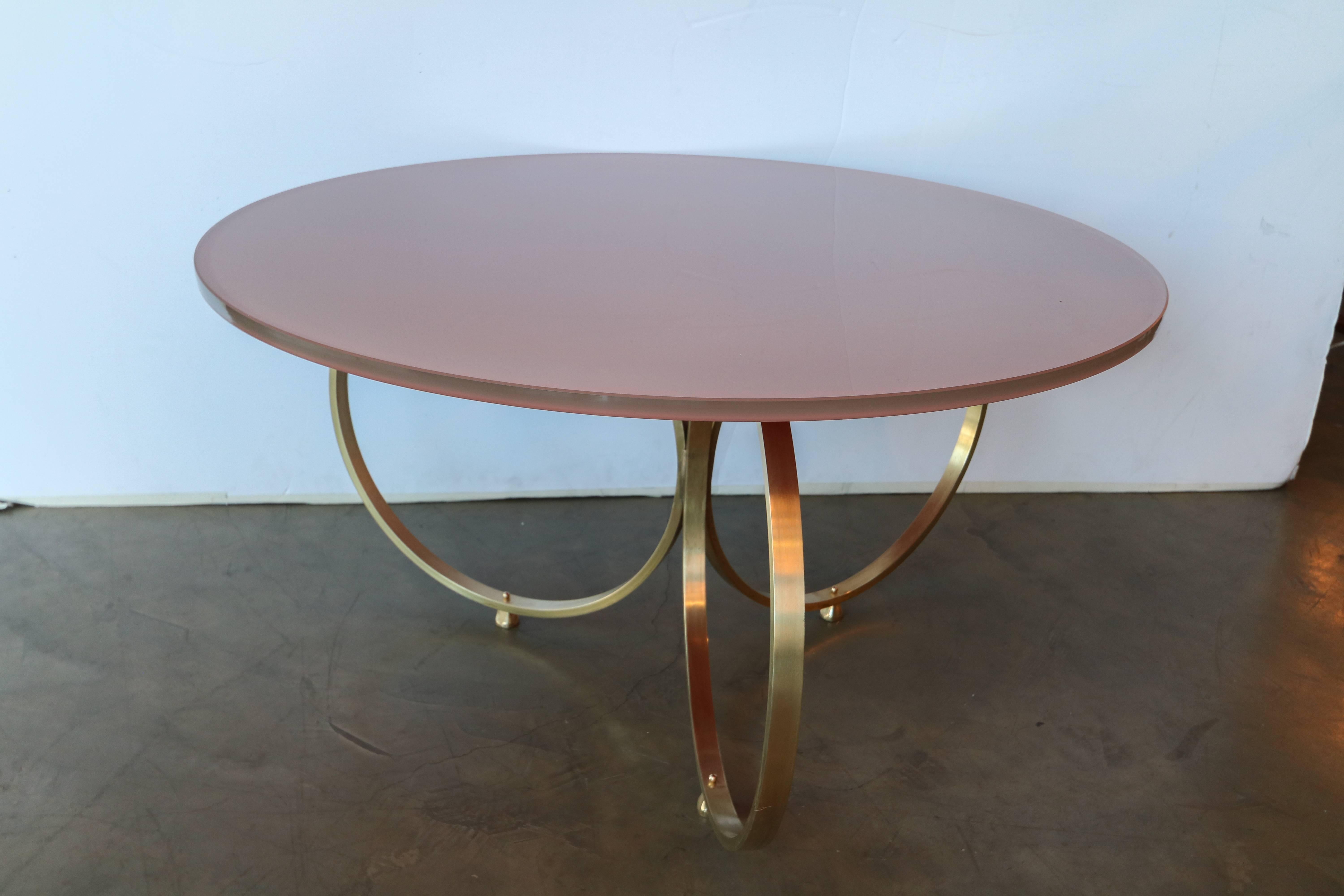 Custom brass coffee table with reverse painted apricot pink glass top and a base of three brass rings. Handmade in Los Angeles by Adesso Imports. Can be done in other colors and finishes.