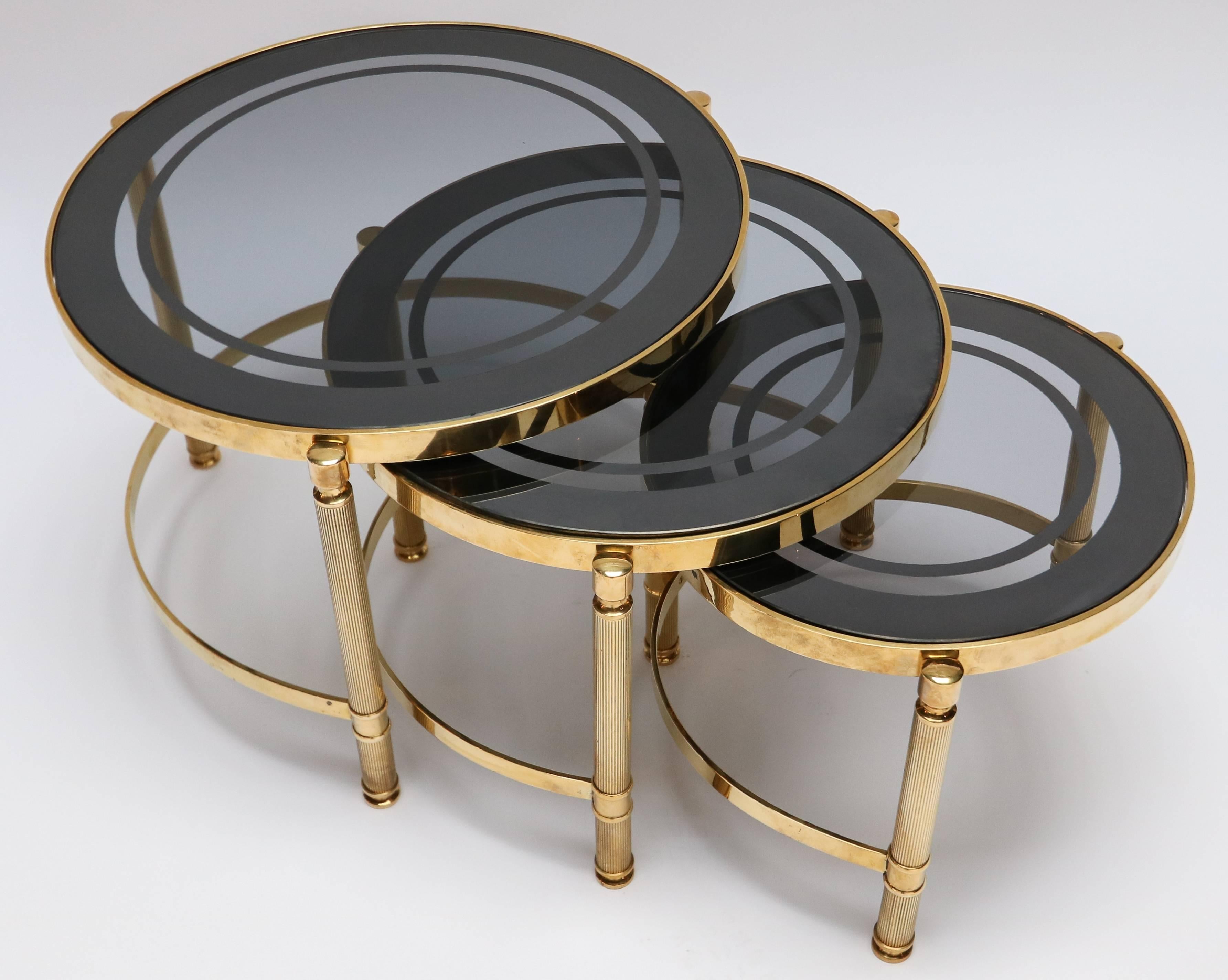 Set of three round brass nesting tables with decorative details and smoked glass tops.

Measures: Small 14.75