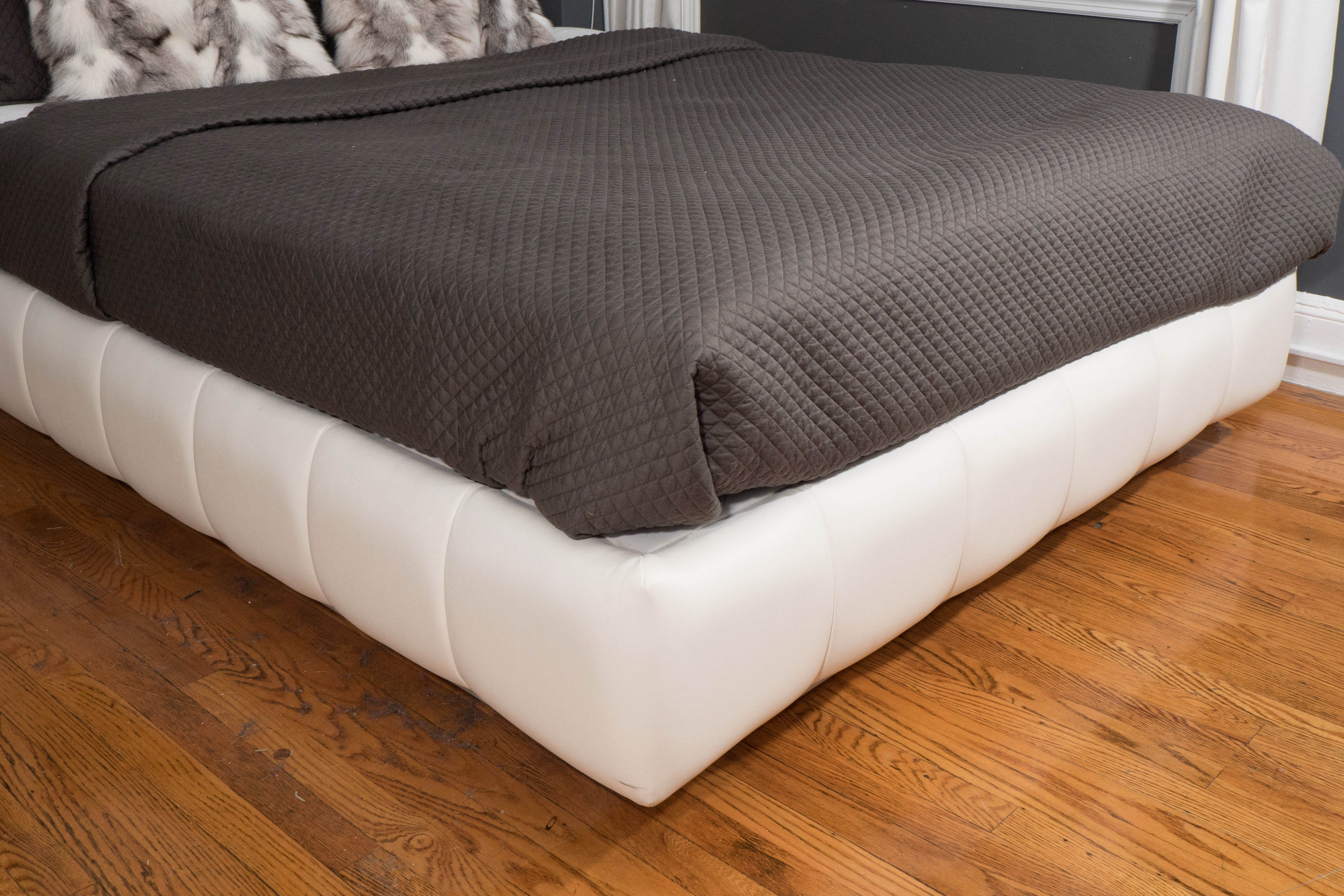 Queen-size white faux leather channel back bed.