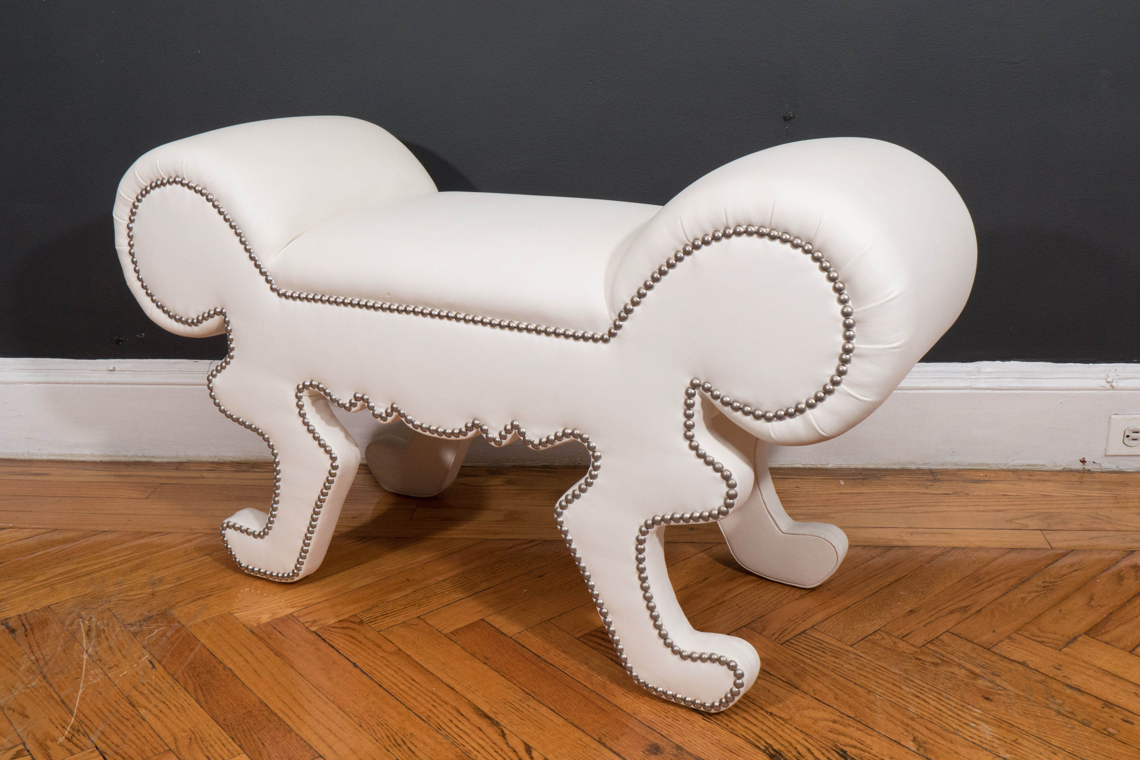 Whimsical bench in white faux leather. This is a floor model that is available as is for immediate purchase. Some wear and blemishes on the upholstery. Additional photos of the recent condition available, and also reupholstery quote can be provided