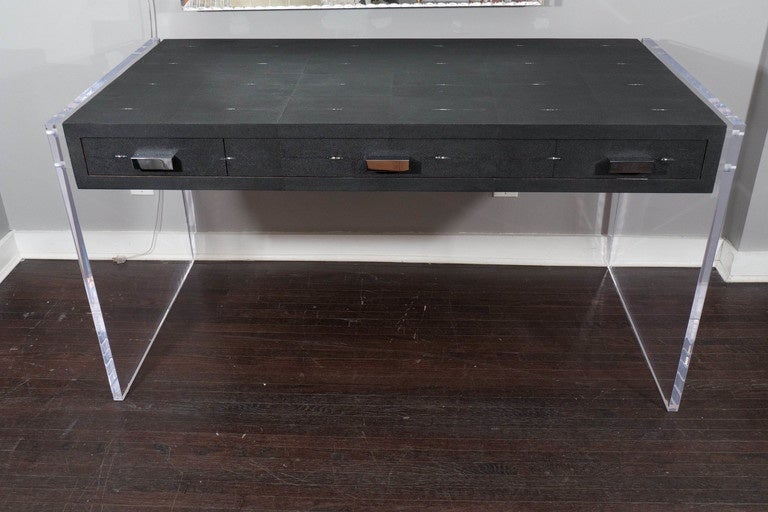 Black shagreen desk with Lucite side panels and 3 drawers with polished nickel pull and finished wood interior. Venfield, NYC. Floor model available for sale. The shagreen top show some wear and aging.