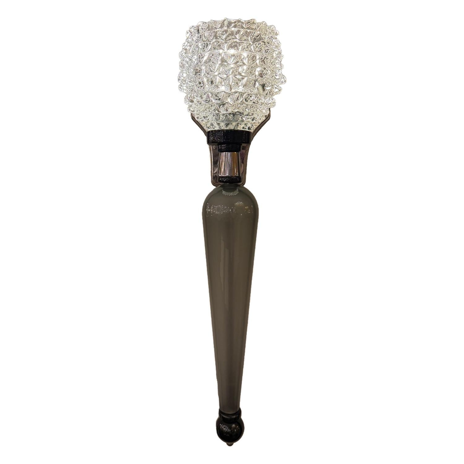 Elegant, sculptural, and undeniably modern—this striking pair of Murano glass sconces features elongated, tapered bodies in smoky grey glass, contrasted by intricately textured crystal shades that catch and refract light beautifully.

The geometric