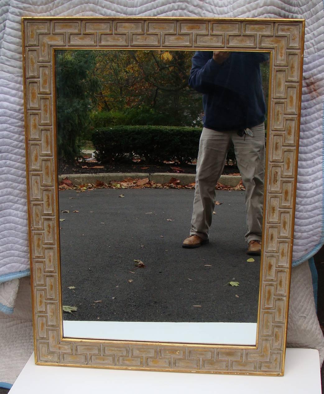 Authentic midcentury mirror.  Wood framing with terrific geometric carving
and finished with paint and gilding.  Always hung in vertical position but easily placed
on horizontal plane.  Strong architectural design which works well with multitude of