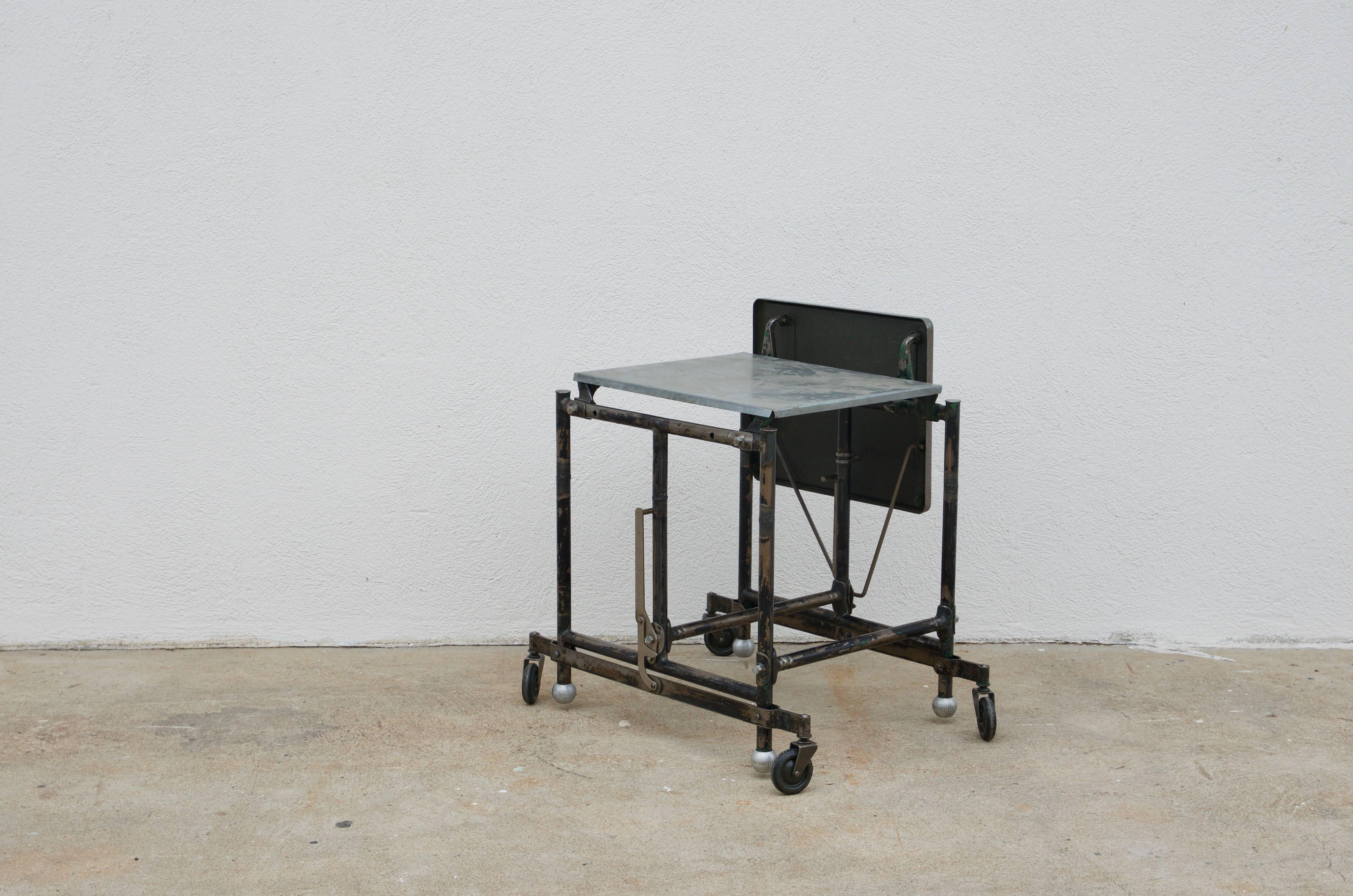 Patinated steel and zinc Industrial rolling side table. Formerly a typewriter stand; great as an Industrial side table or nightstand. Great patina. Fully functional.