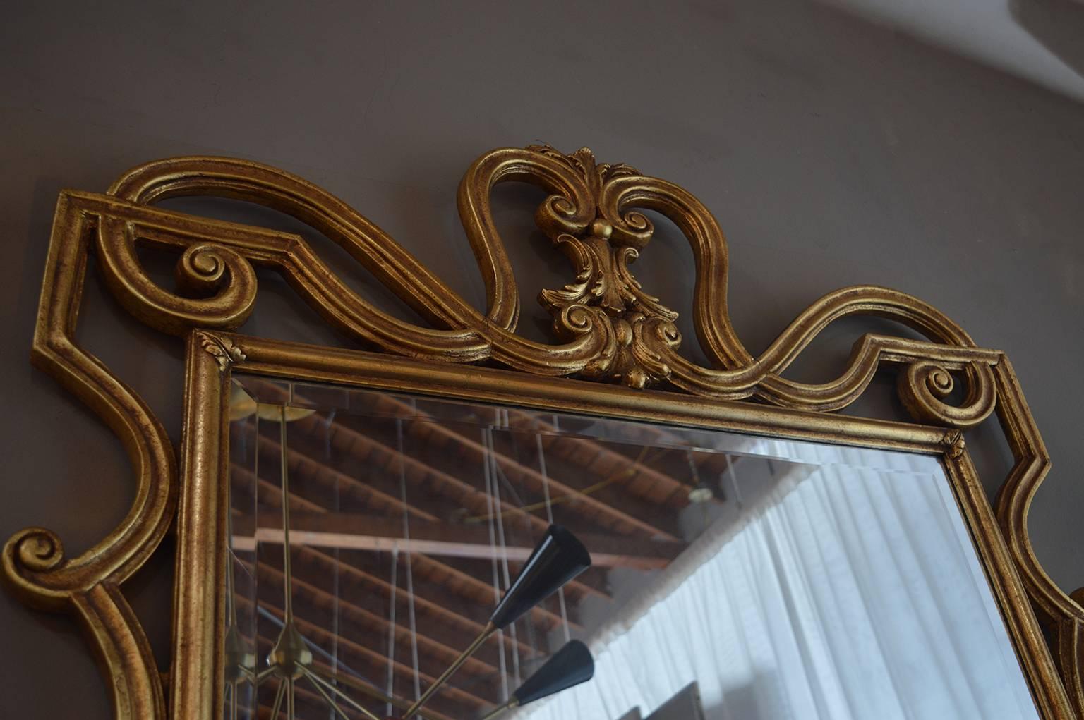 The frame of the mirror is hand-carved wood with beautiful details and gold leafed.