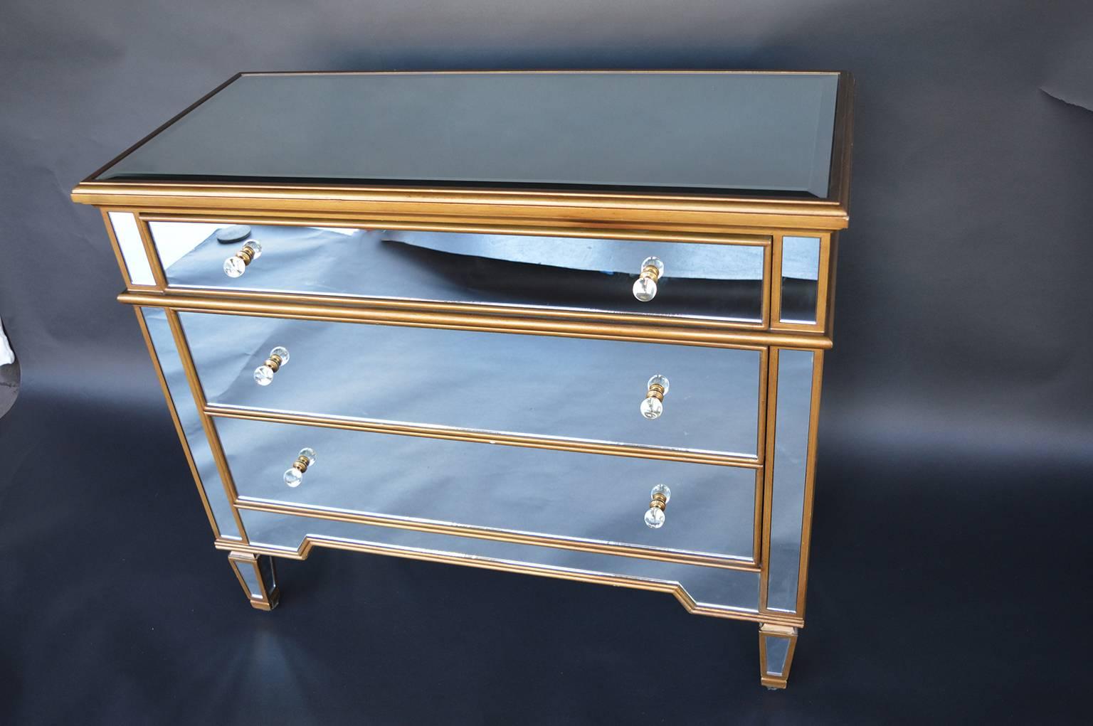 Pair of mirrored drawers with gold accents.