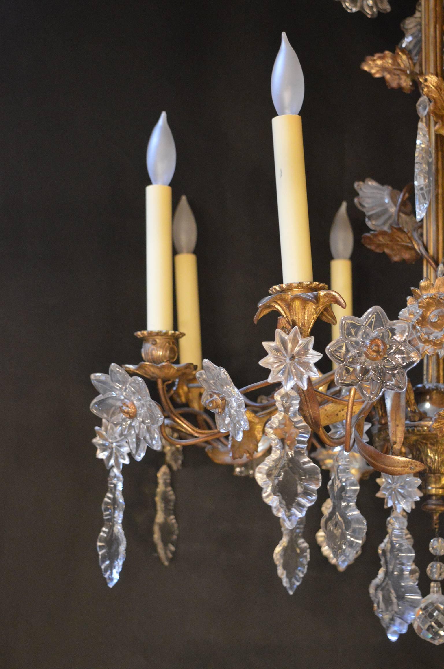 Chandelier has floral details. There is a brass vine wrapped around the arms of the chandelier as well a climbing to the top to create the canopy. Crystal creates the florets on each arm.