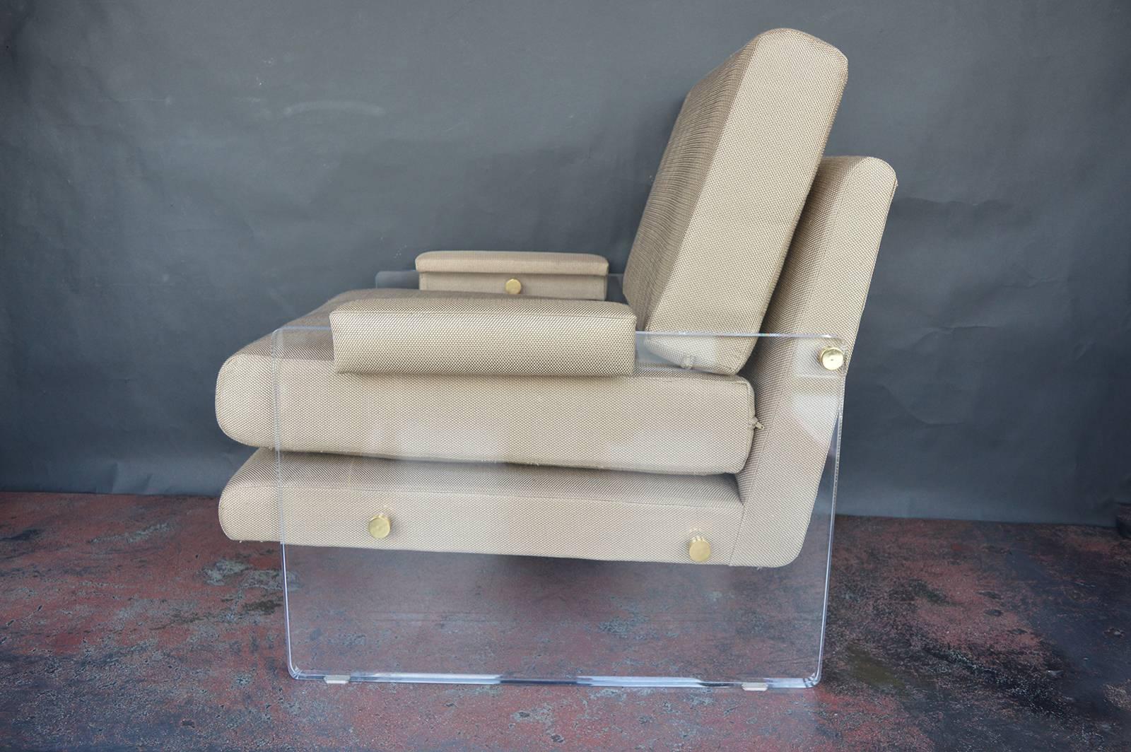 Pair of Lucite armchairs with brass hardware.