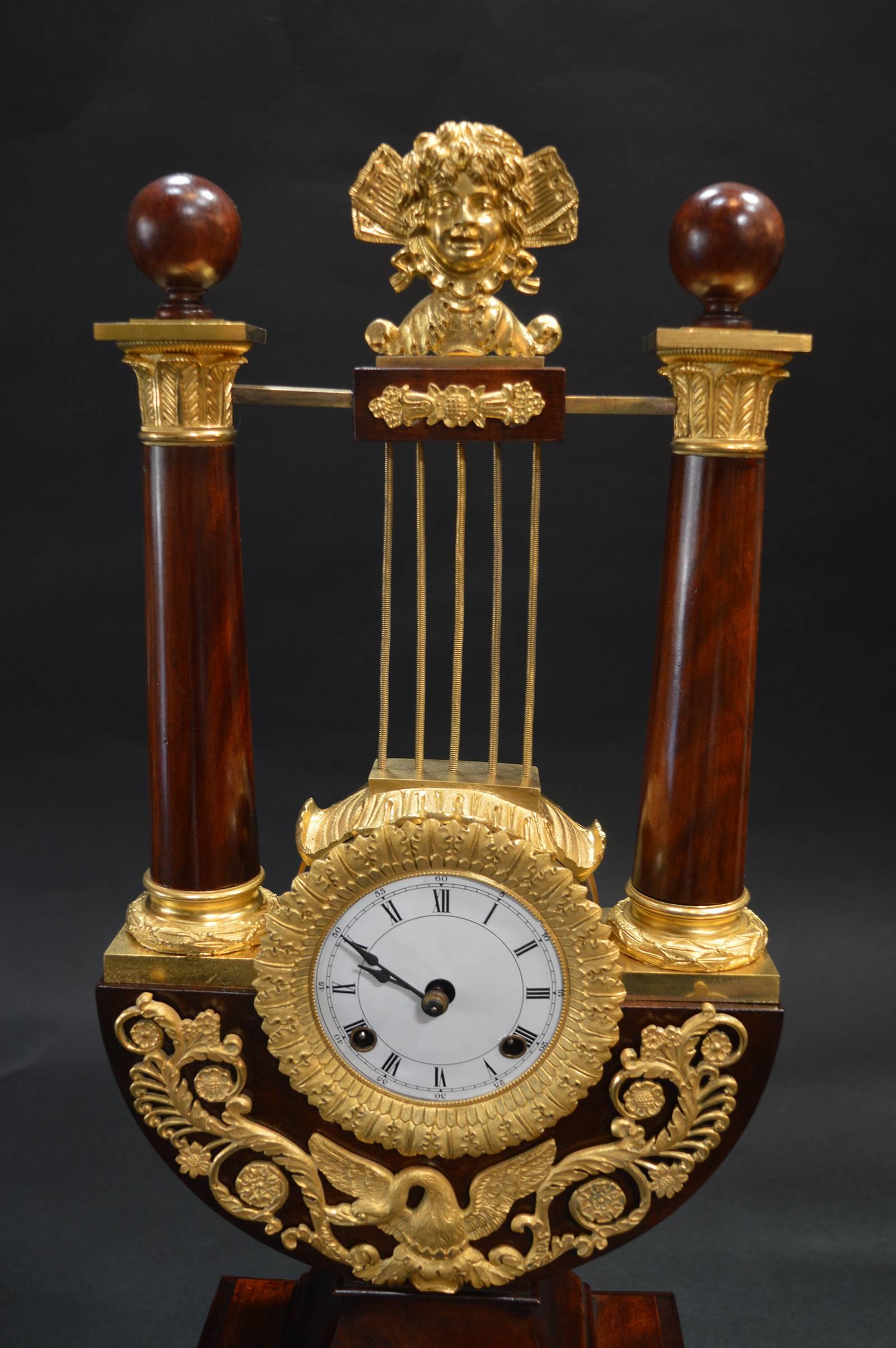Empire mahogany clock with gilded ormolu clock is in working condition.
