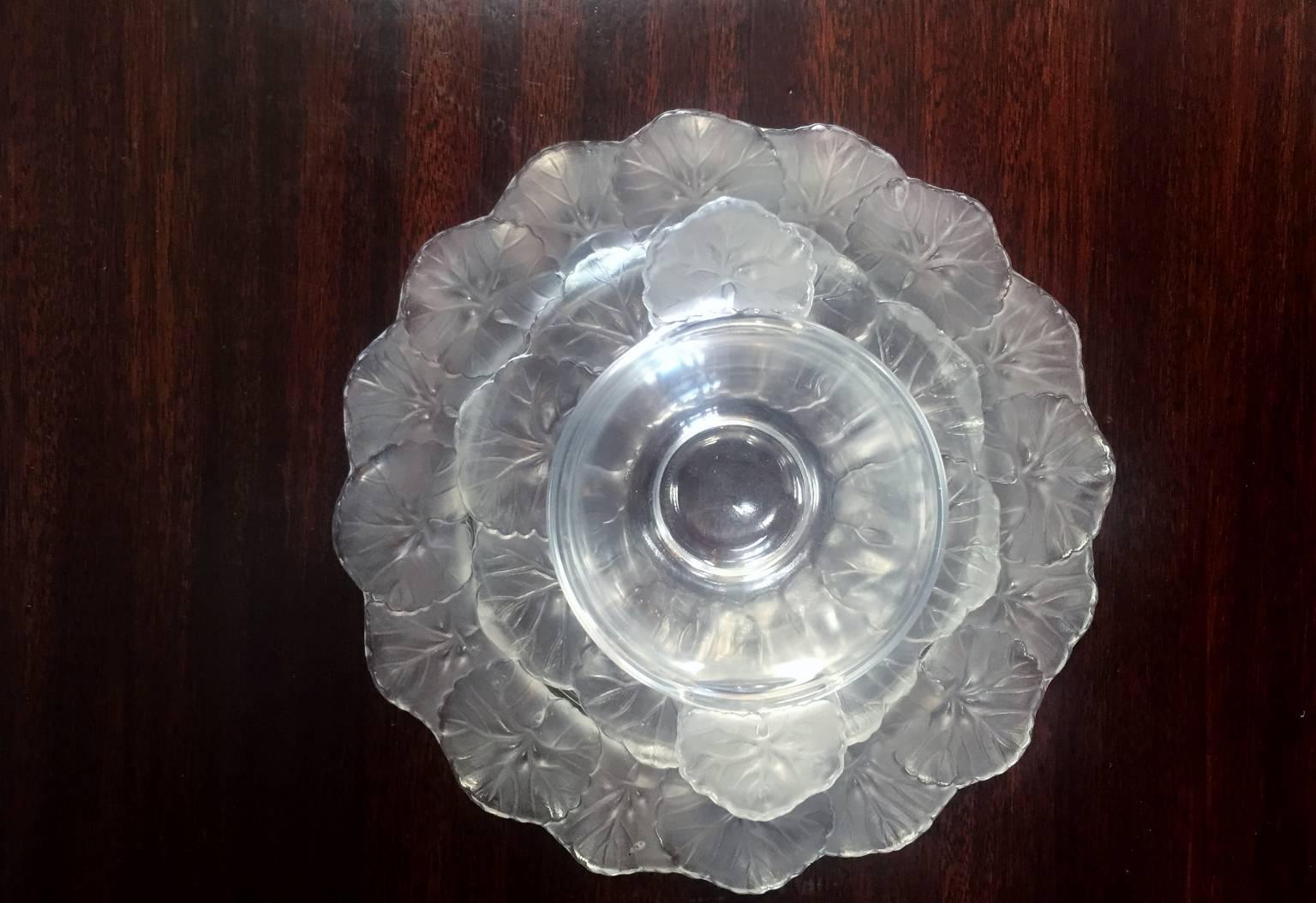Lalique glass dessert set. The edges of the plates are decorated with leaves, as well as the edge of the small ice cream dish has small leaf handles.
The small bowl is 5.50 D x 2.50 H.
The small plate is 6