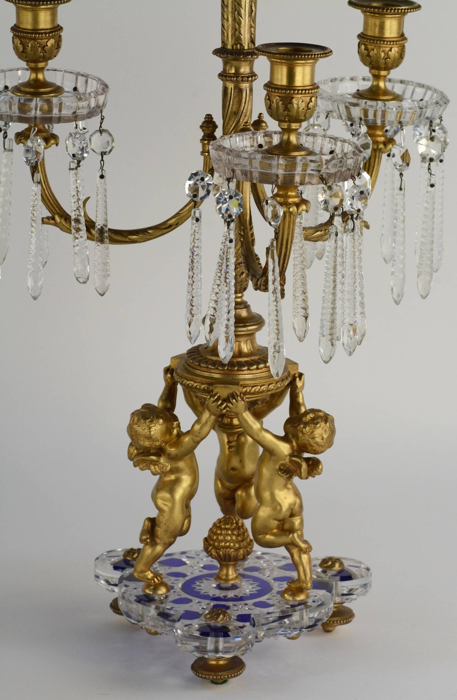 Pair of ormolu-mounted Baccarat candelabra. Bronze gilded cherubs dancing on top of crystal with blue accented bases.
