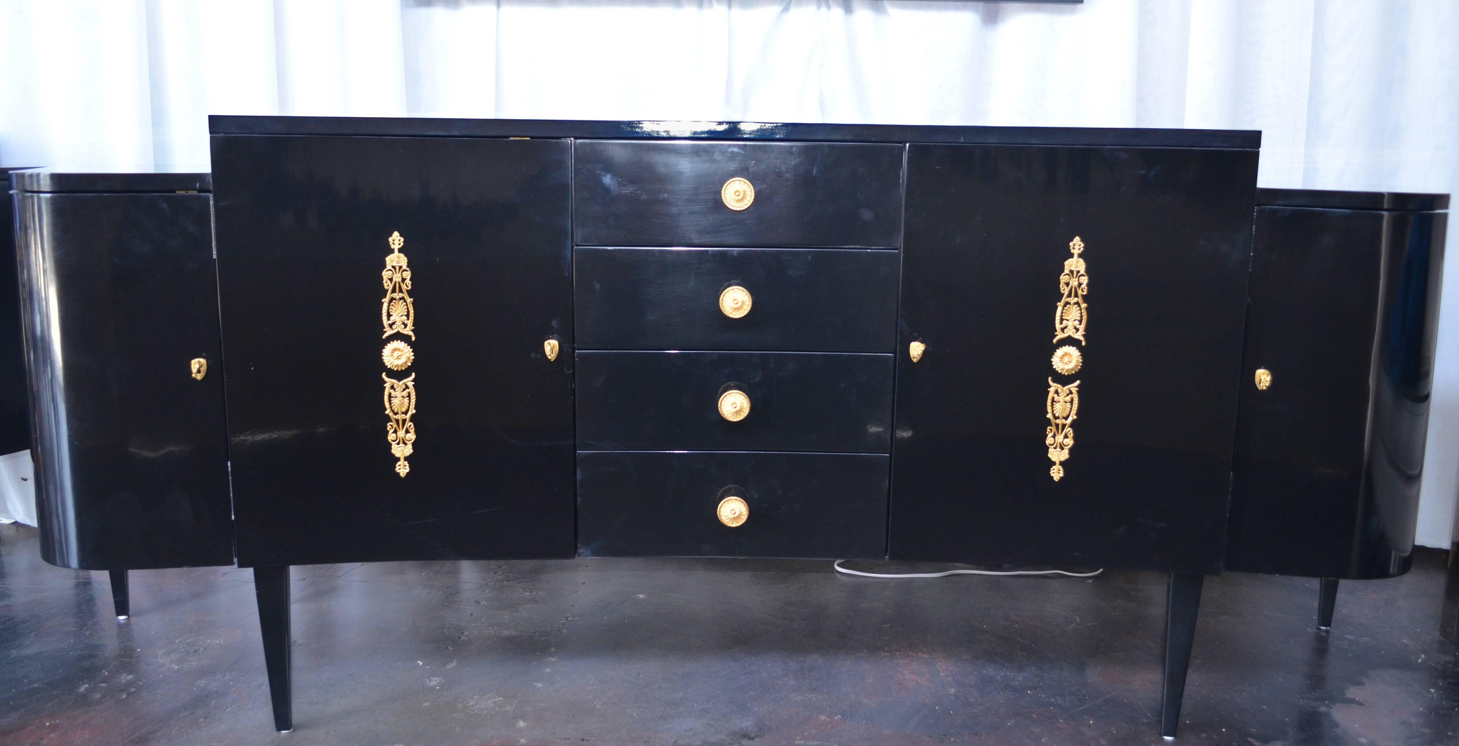 Pair of black lacquer commodes by Kelly Wearstler. The commodes have four front drawers with detailed gold finished bronze knobs. As well as four shelved cabinets with gold accents.