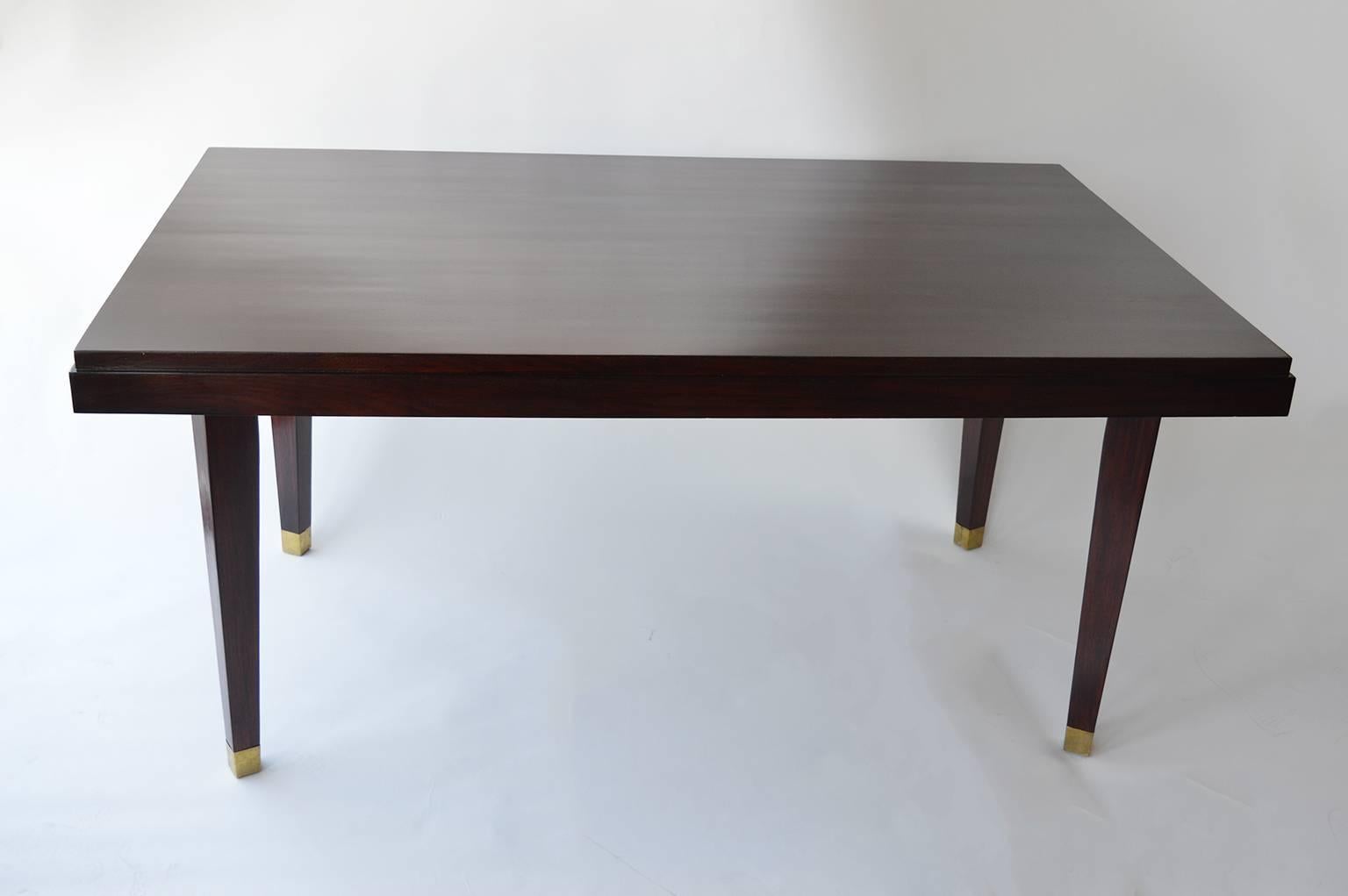 Mid-Century modern dining table. Legs of the mahogany table are capped and accented with brushed brass feet.
The tables full width with extensions is 90.5 inches.