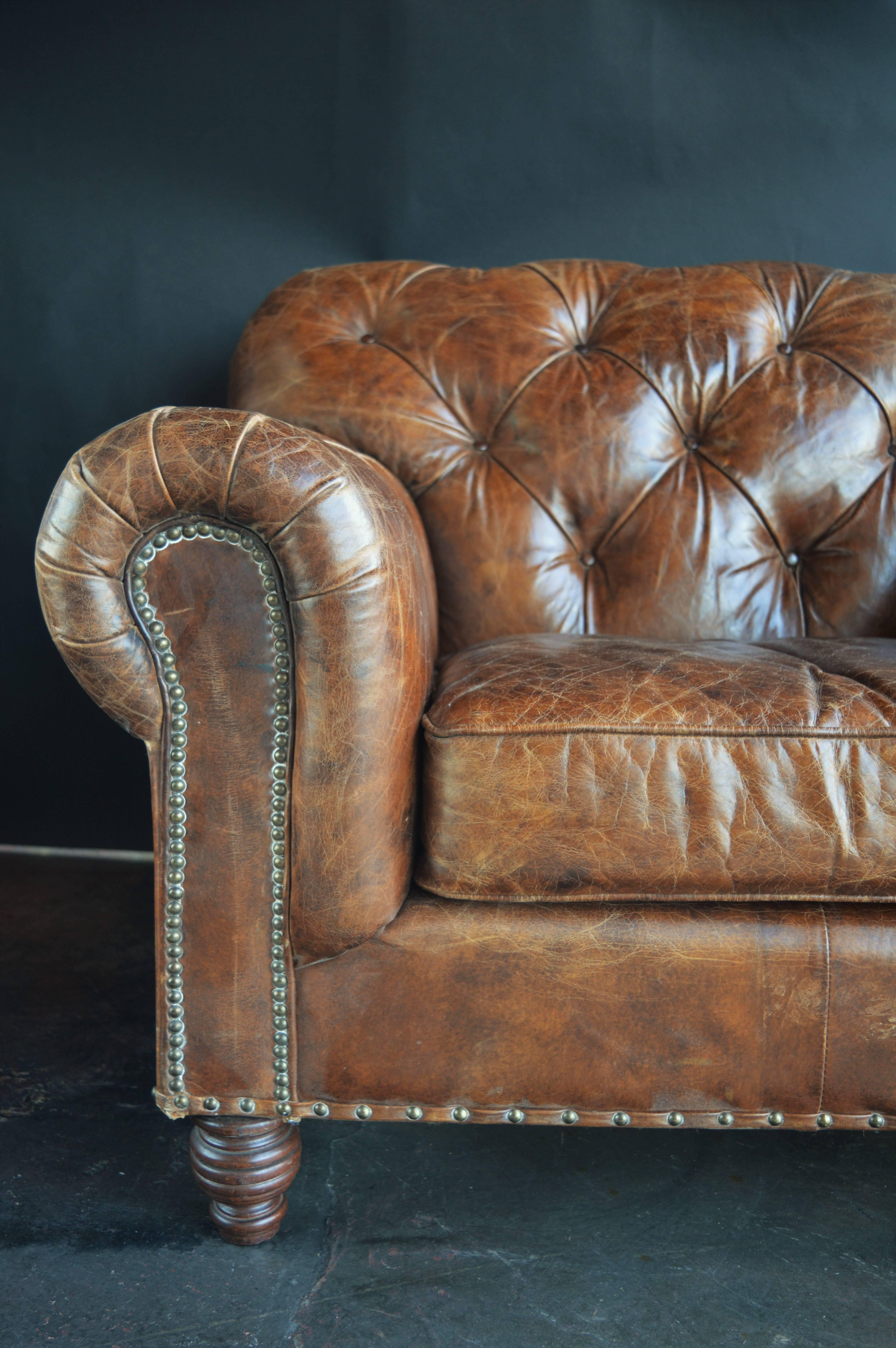 Pair of leather Chesterfield club chairs with distressed leather. Tufted button-back.