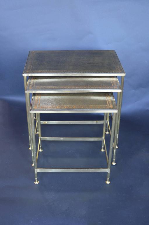 Maison Jansen nesting tables with gold detailed leather tops. The feet are bronze with brass legs.