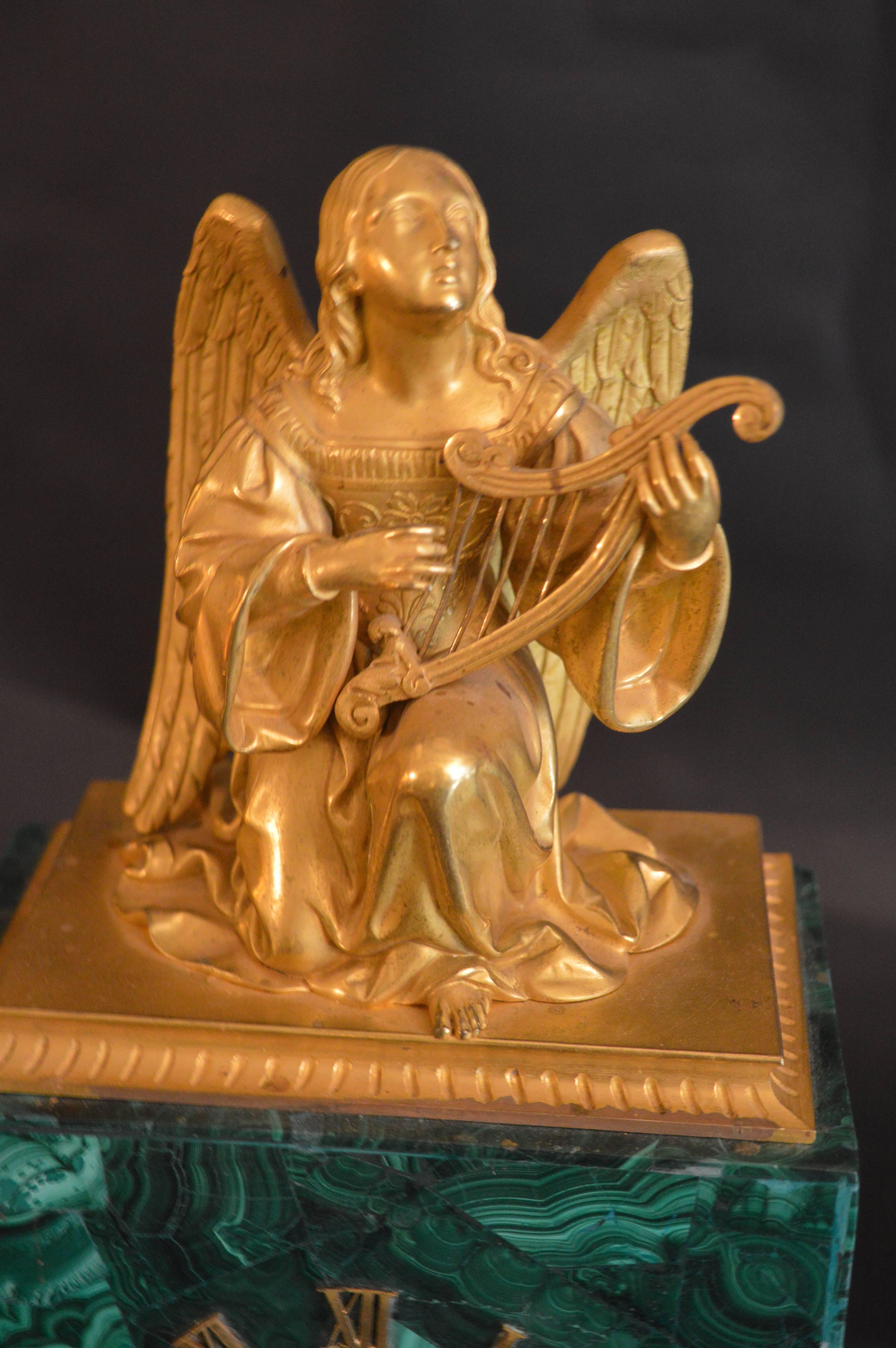 Malachite clock with gilded angel on top.