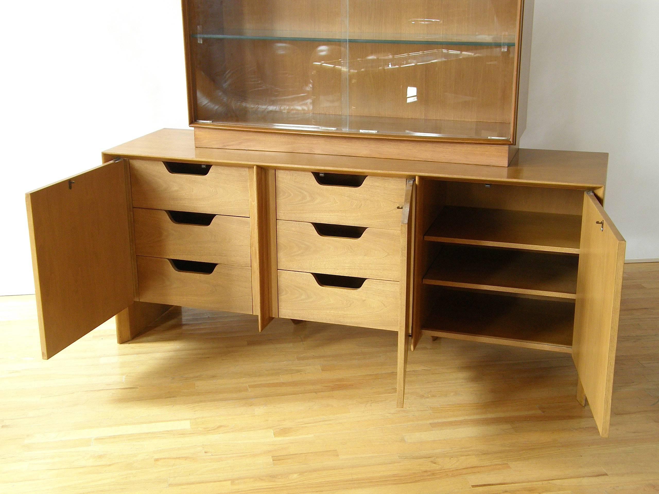 This handsome sideboard designed by T. H. Robsjohn-Gibbings for Widdicomb has a china / display cabinet top piece with sliding glass doors. (Shown without the doors in some of the photos.) The lower piece has three doors. Behind the two on the left