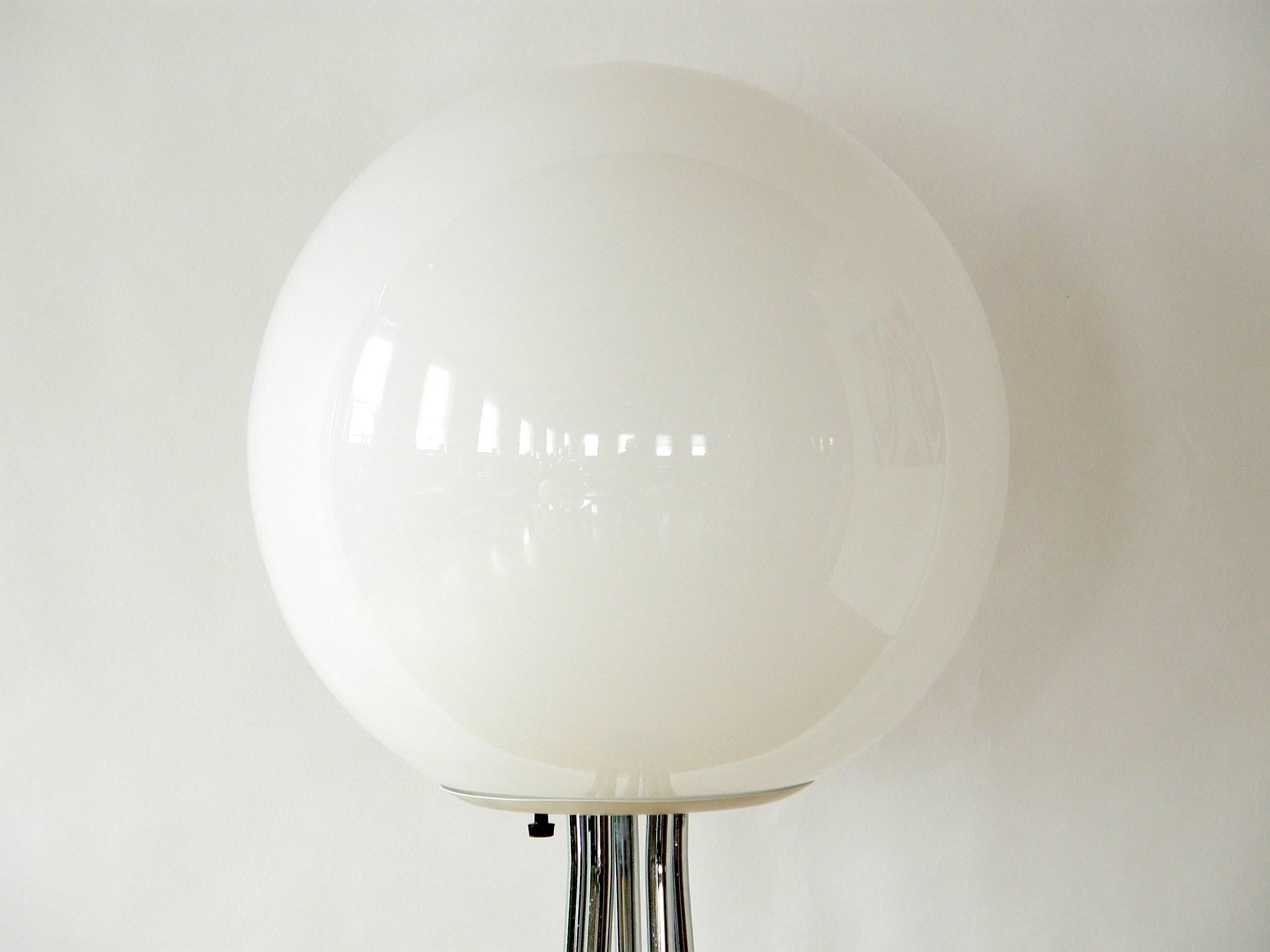This mid-century modern floor lamp has a round black base, five chrome stems forming a tapered stand and a white glass globe shade. It throws a broad, indirect light.

Please let us know if you have any questions.