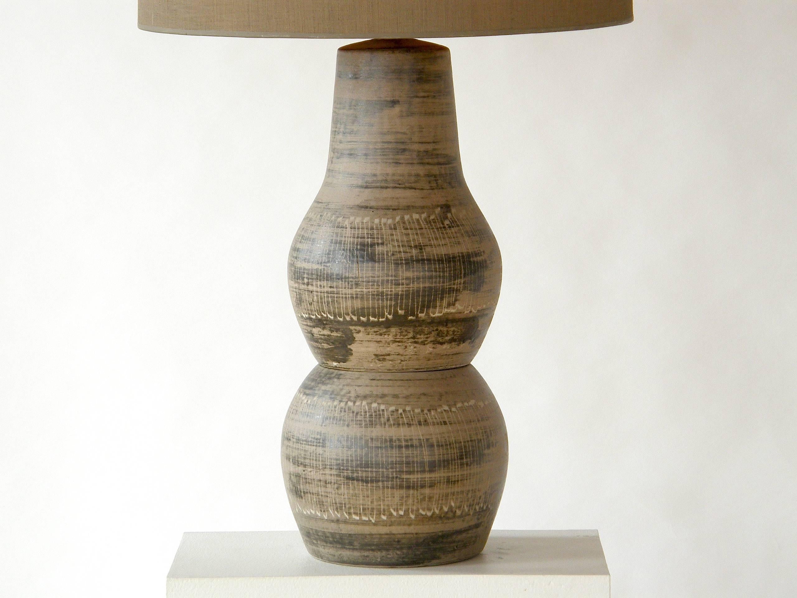 Ceramic table lamp with incised decoration and original turned wood finial by Jane and Gordon Martz. This design is shown in their 1955 catalog.

Overall- 
18