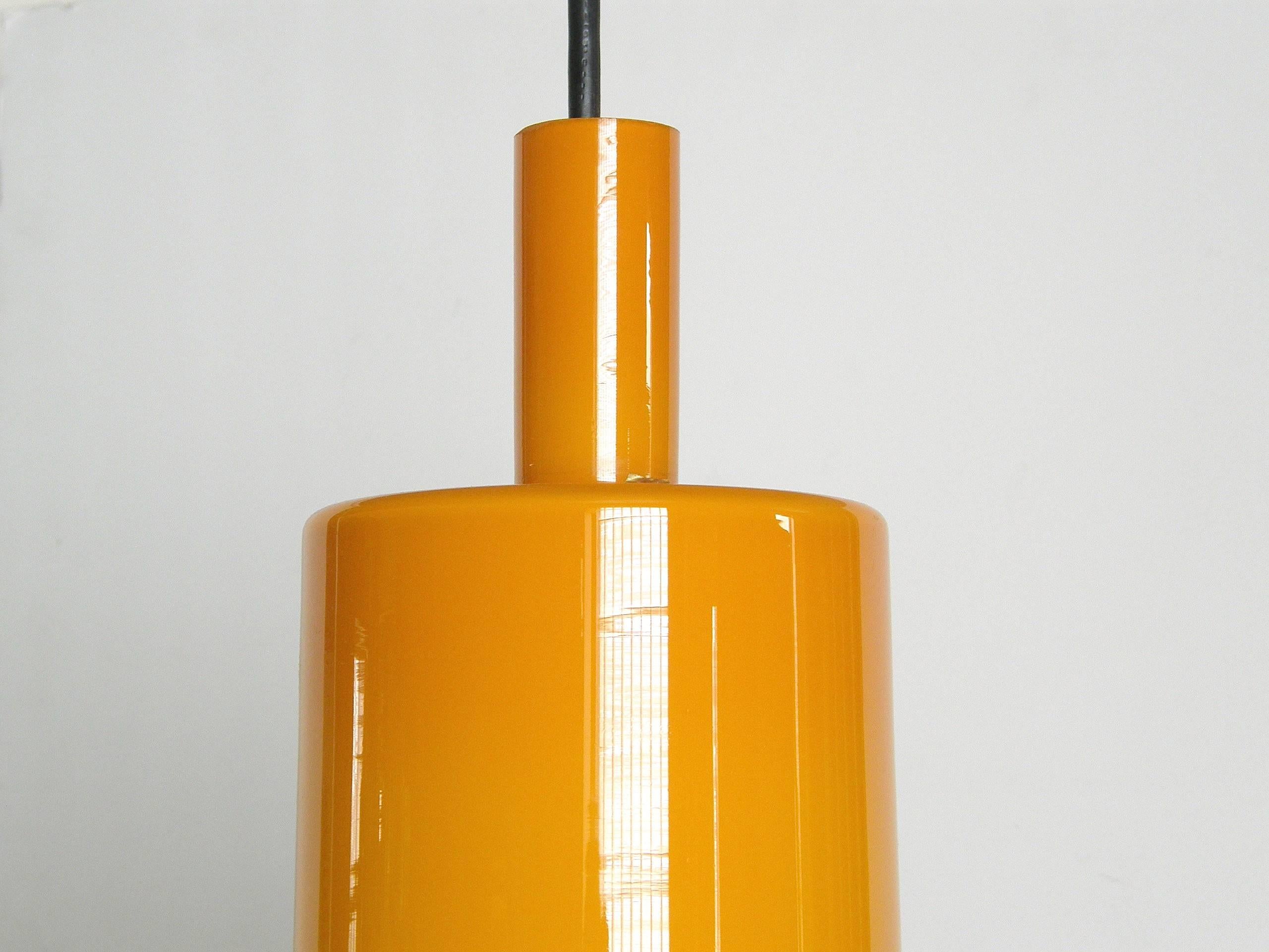 This new/old stock glass ceiling fixture was designed by Jo Hammerborg for Fog & Mørup of Denmark. The glass shade was made by Holmegaard in bright orange cased in white, and it has a warm glow when lit. It retains its manufacturer's stickers and