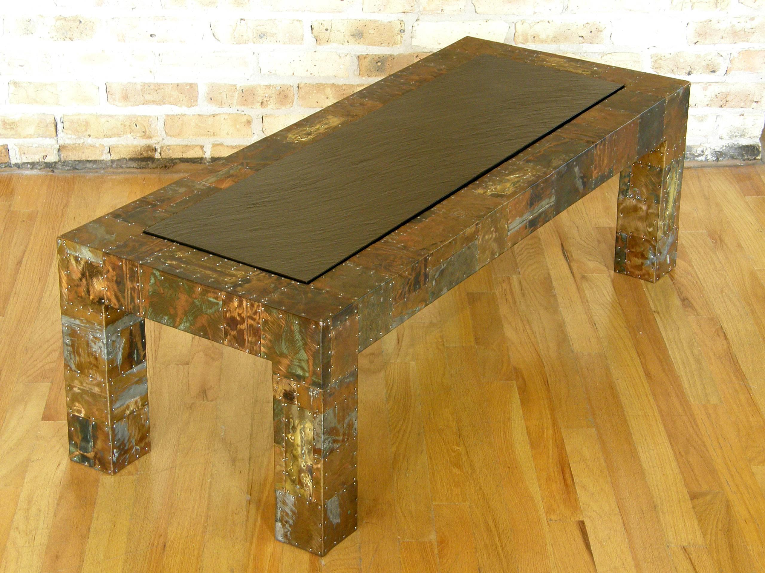 Studio made coffee table with patchwork copper and brass clad surface. The metal pieces are patinated and enameled with applied, torch cut, and ground down textures in the finish. The nailheads that attach the various pieces are a tactile and